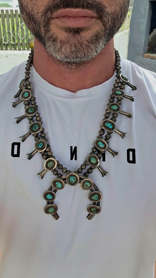 An absolutely breathtaking and exceptionally rare vintage Native American Navajo squash blossom necklace, masterfully handcrafted in sterling silver and adorned with vivid turquoise cabochons throughout.