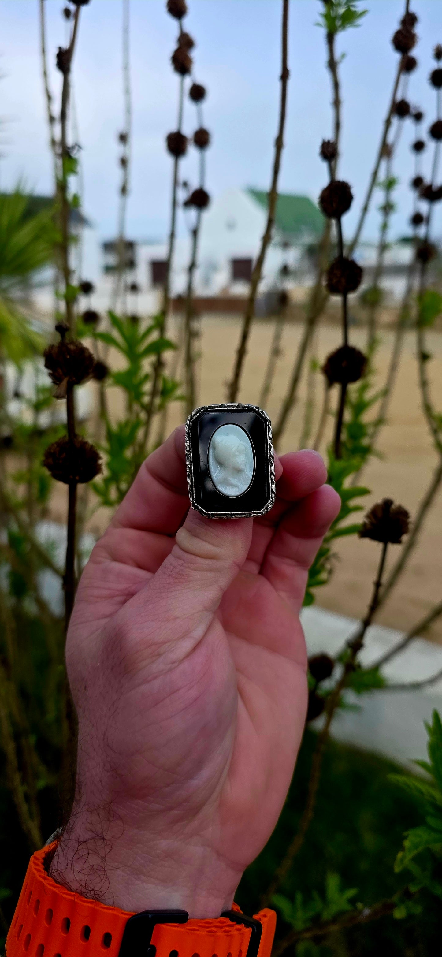 This beautiful vintage brooch features a striking oval milk glass cameo depicting the graceful profile of a young lady, her delicate features sculpted in crisp relief against a dramatic black glass background.