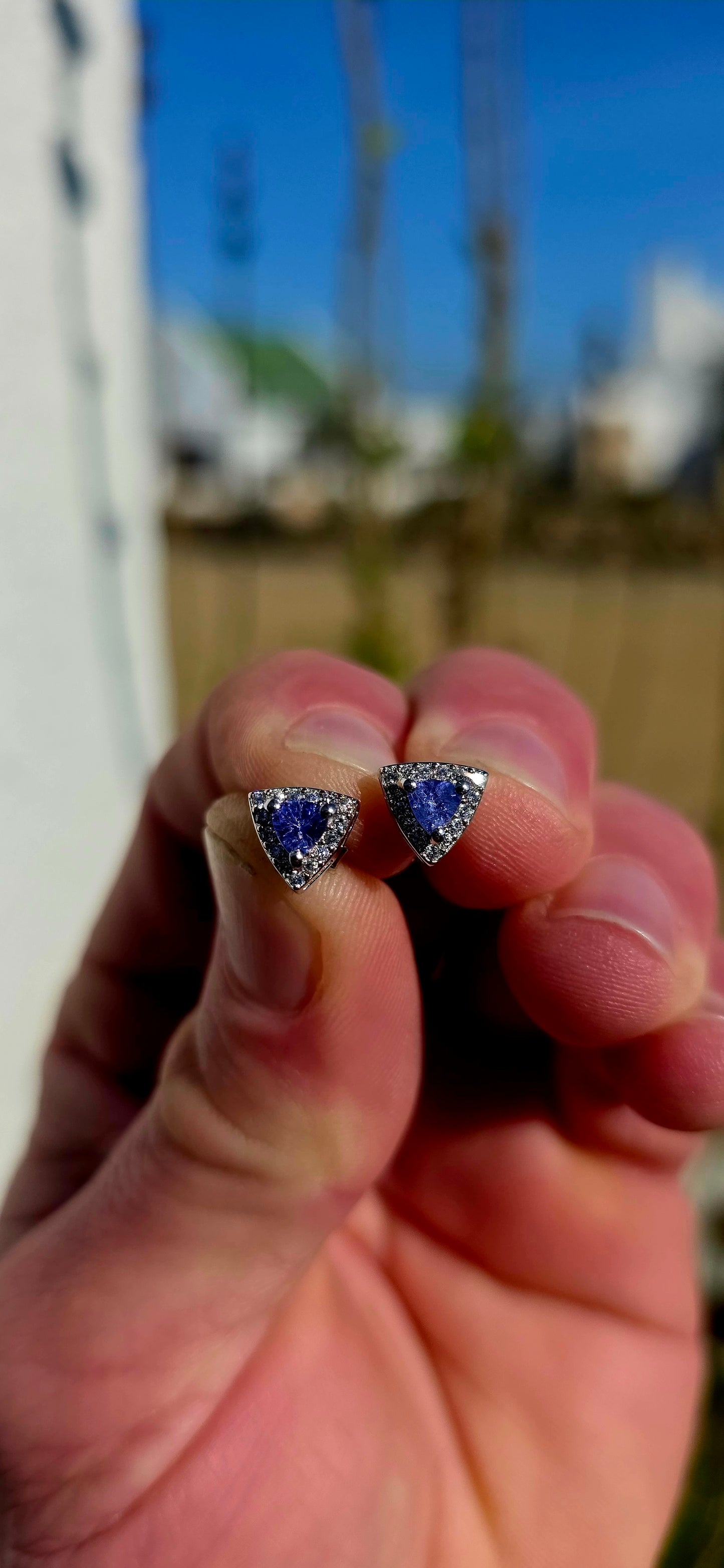 Crafted in sterling silver, these elegant stud earrings feature beautiful prong-set trillion cut tanzanites glowing in rich shades of violet-blue, indigo, and twilight lavender .
