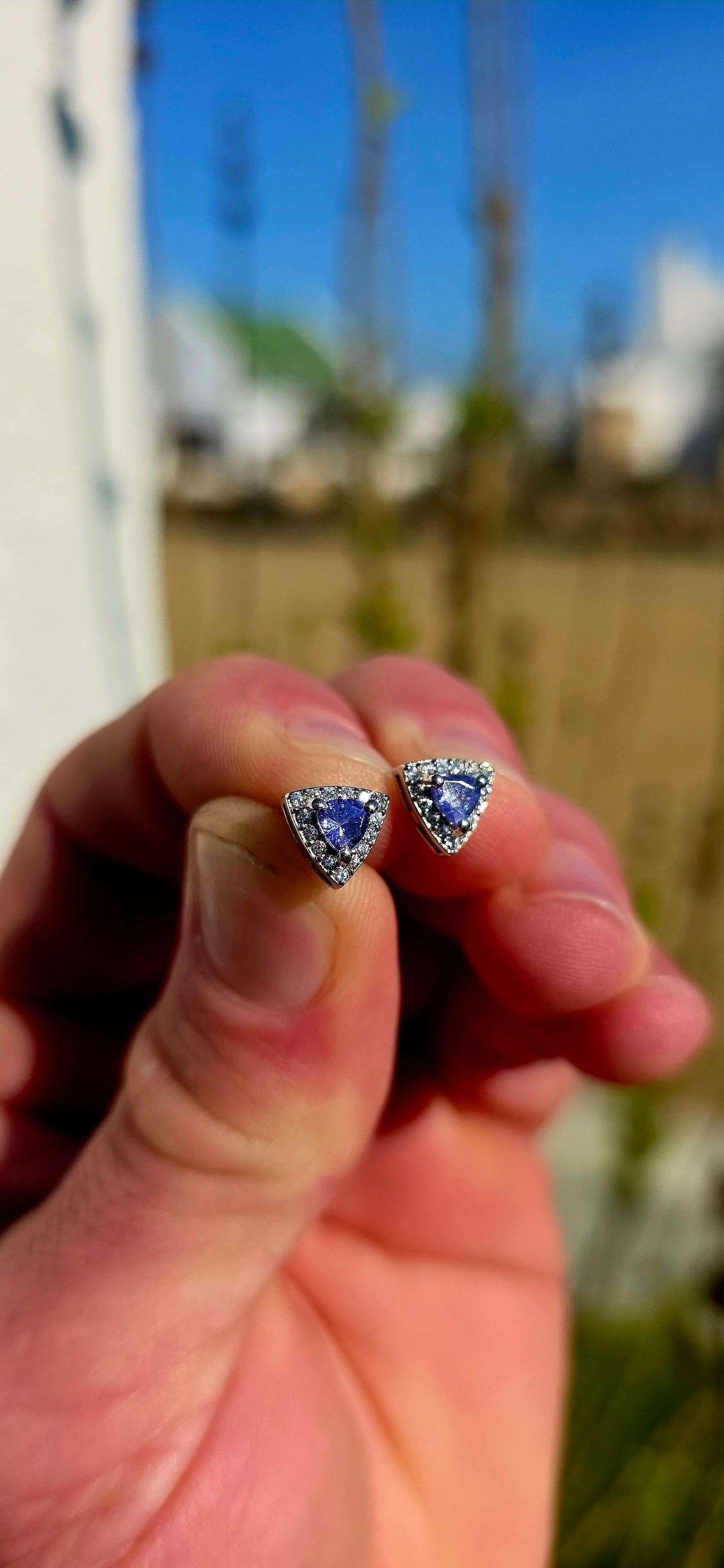 Crafted in sterling silver, these elegant stud earrings feature beautiful prong-set trillion cut tanzanites glowing in rich shades of violet-blue, indigo, and twilight lavender .