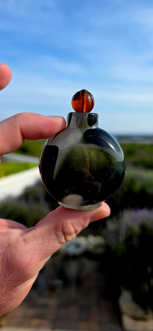 This rare 19th-century Chinese snuff bottle has been expertly crafted from striking marbled glass designed to imitate natural banded agate, a highly prized material in traditional Chinese decorative arts.