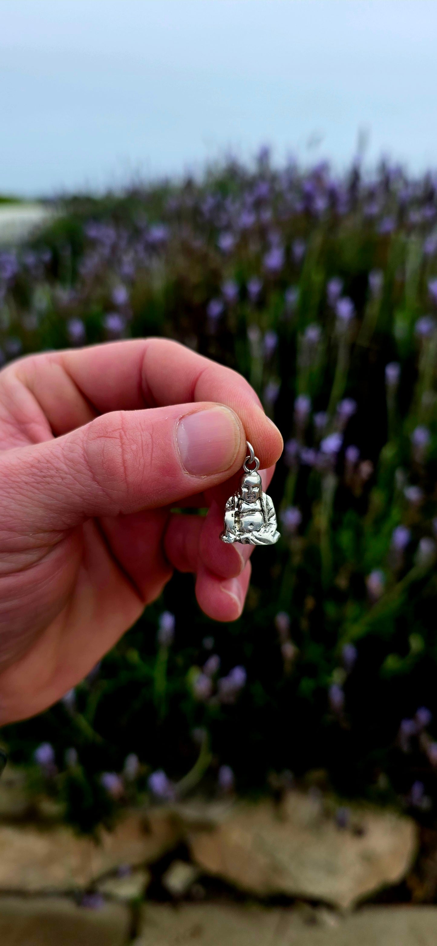 A beautiful solid and weighty vintage sterling silver charm depicting a seated Buddha in a peaceful meditative pose .