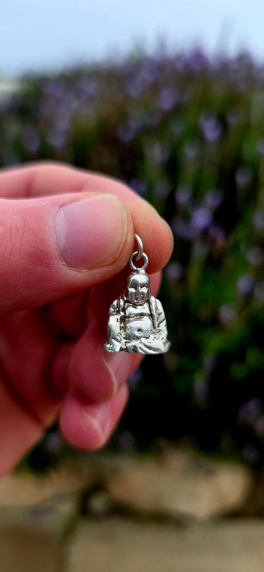 A beautiful solid and weighty vintage sterling silver charm depicting a seated Buddha in a peaceful meditative pose .