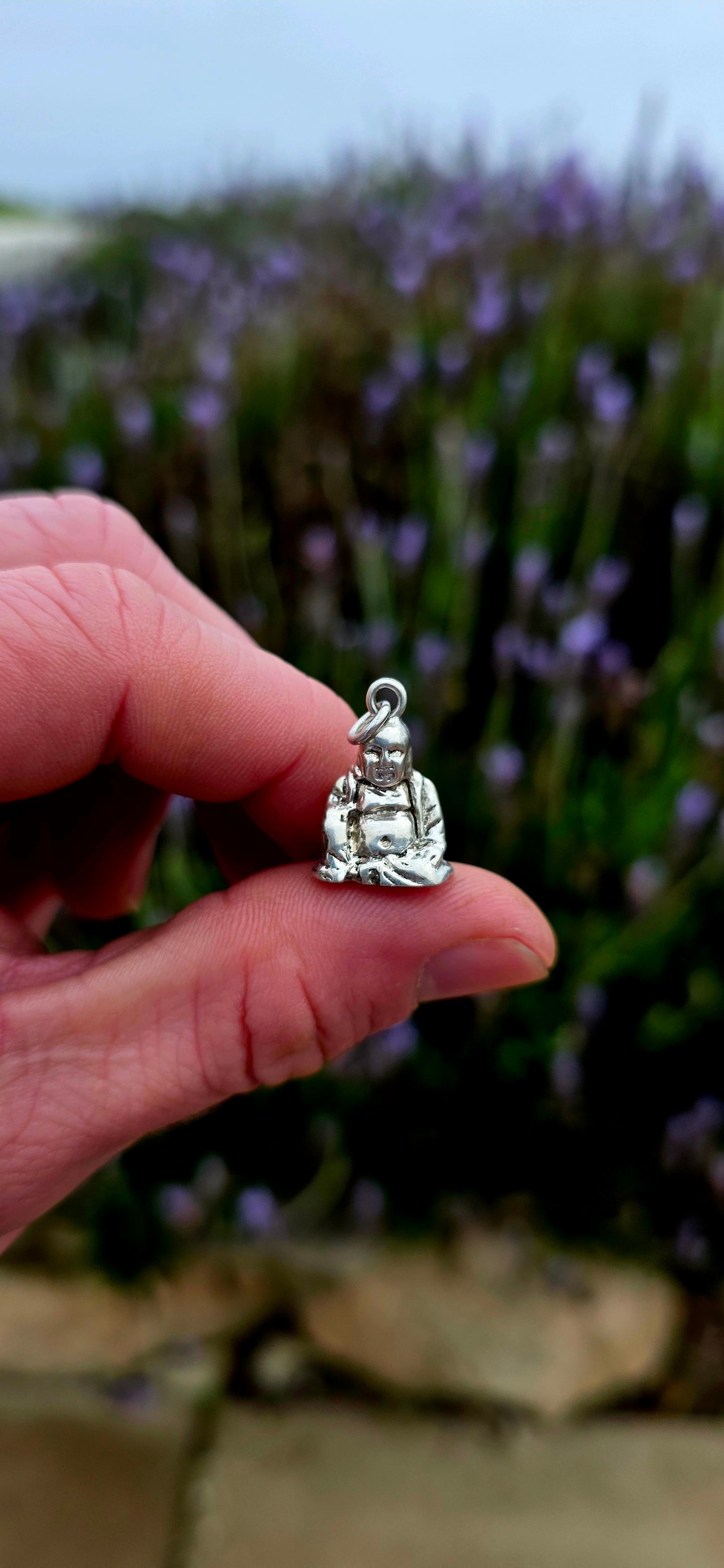 A beautiful solid and weighty vintage sterling silver charm depicting a seated Buddha in a peaceful meditative pose .