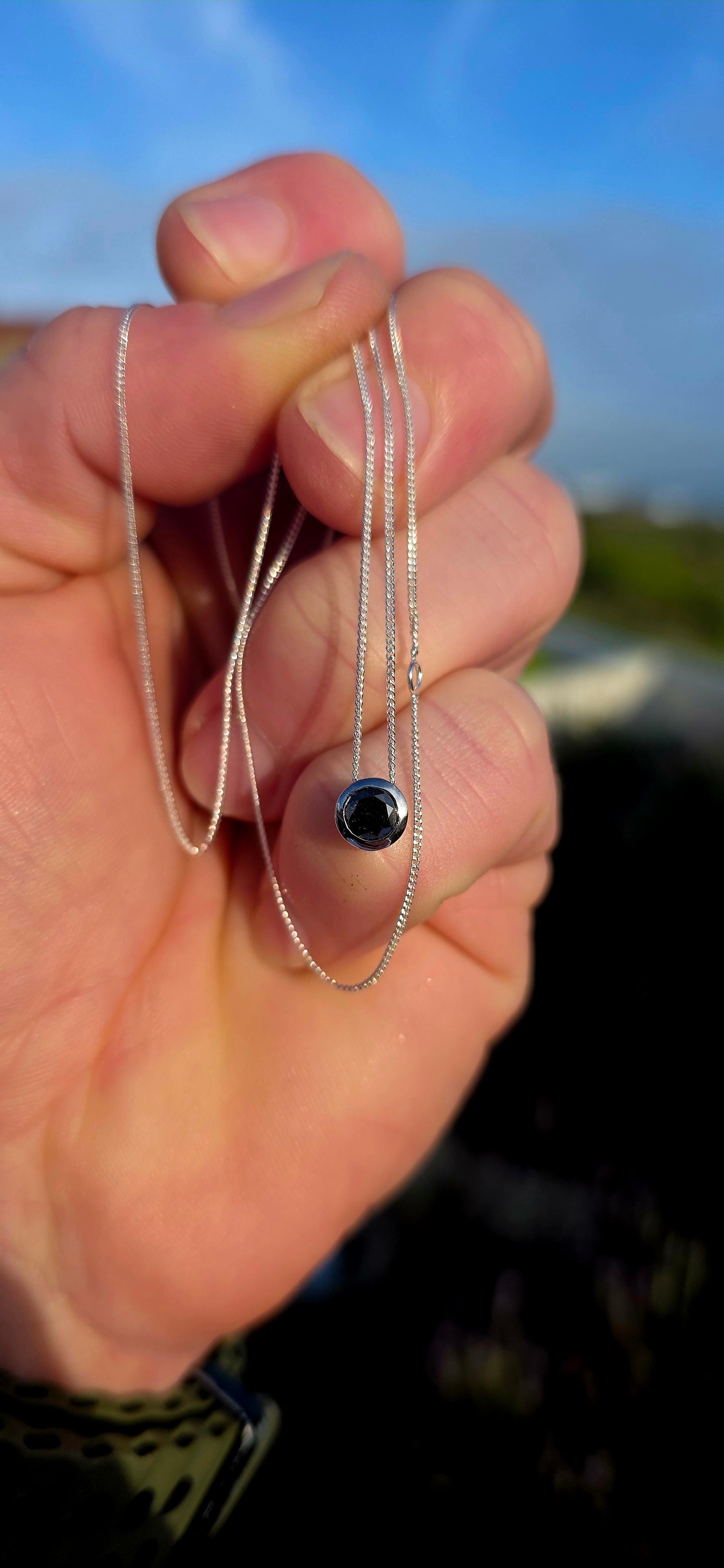 This elegant unisex sterling silver necklace embraces the beauty of simplicity, featuring a single round faceted black diamond securely nestled within a sleek tube setting.