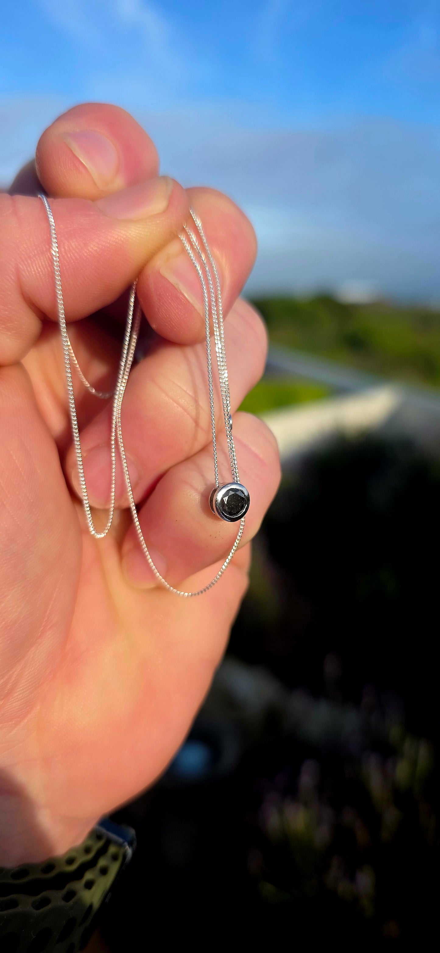 This elegant unisex sterling silver necklace embraces the beauty of simplicity, featuring a single round faceted black diamond securely nestled within a sleek tube setting.