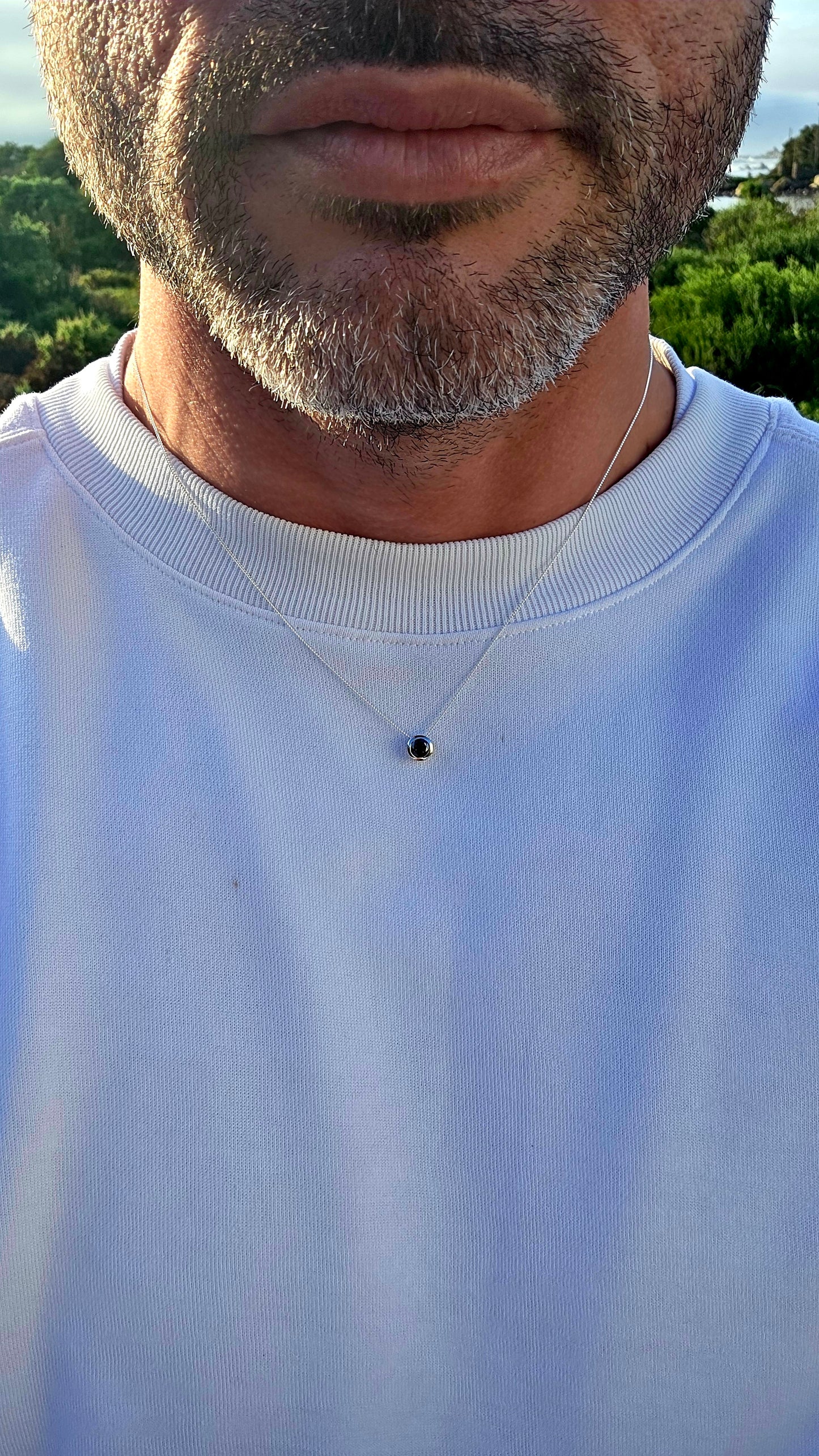This elegant unisex sterling silver necklace embraces the beauty of simplicity, featuring a single round faceted black diamond securely nestled within a sleek tube setting.