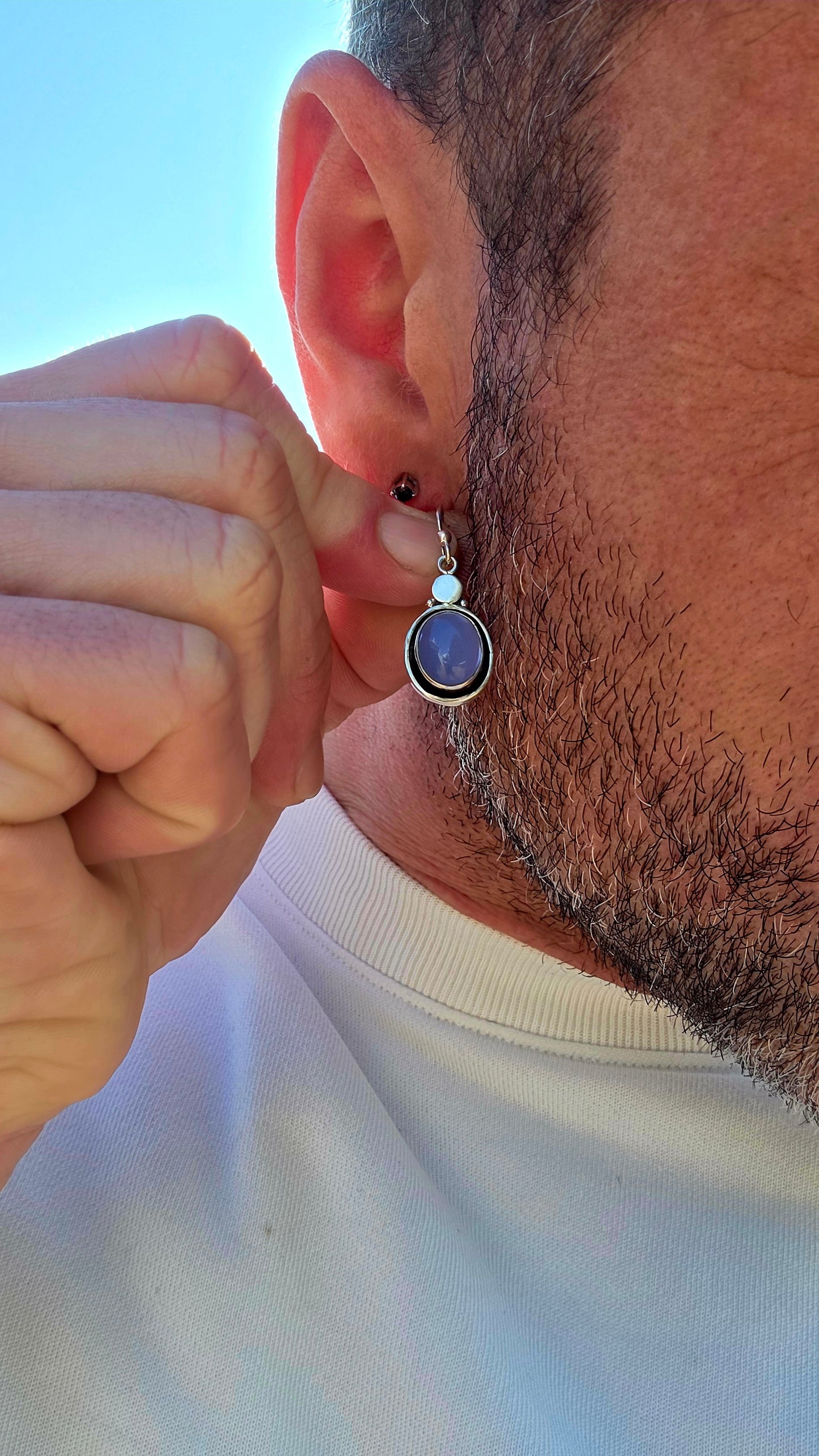 This artisan-made pair of sterling silver drop earrings features smooth, oval lavender-blue chalcedony cabochons, each beautifully tube-set in polished silver.