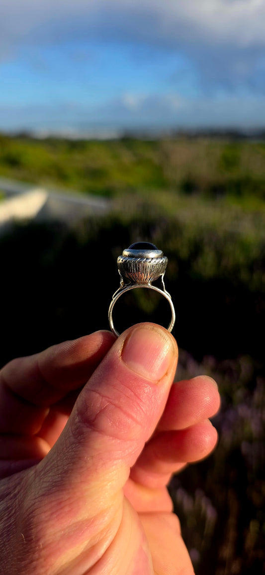 This striking handcrafted Kabwe sterling silver ring features a glowing rounded amethyst cabochon, elegantly tube-set within a beautifully raised and richly textured domed setting.