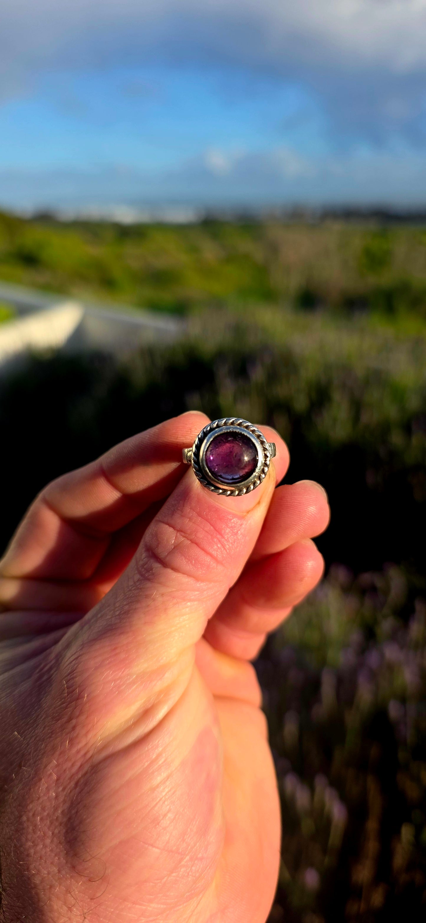 This striking handcrafted Kabwe sterling silver ring features a glowing rounded amethyst cabochon, elegantly tube-set within a beautifully raised and richly textured domed setting.