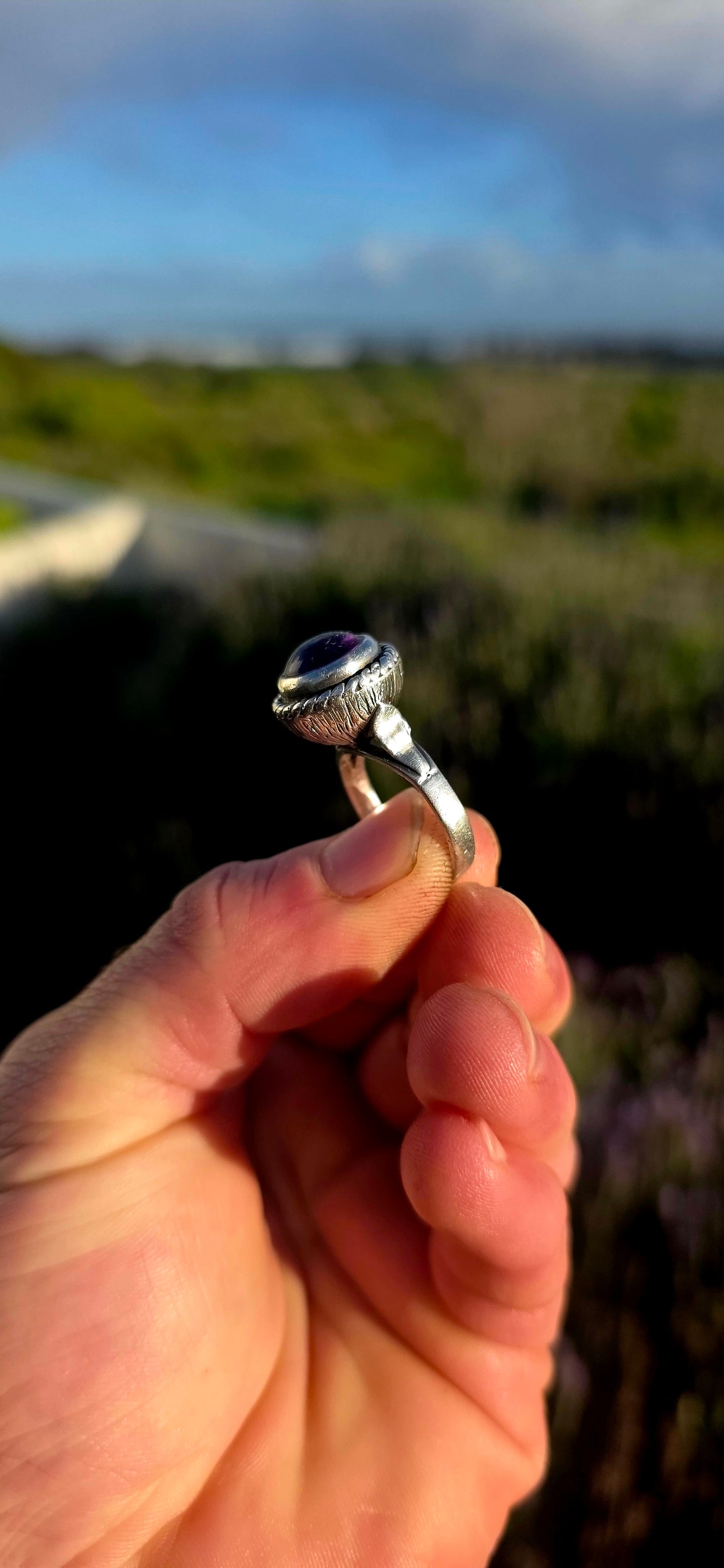 This striking handcrafted Kabwe sterling silver ring features a glowing rounded amethyst cabochon, elegantly tube-set within a beautifully raised and richly textured domed setting.