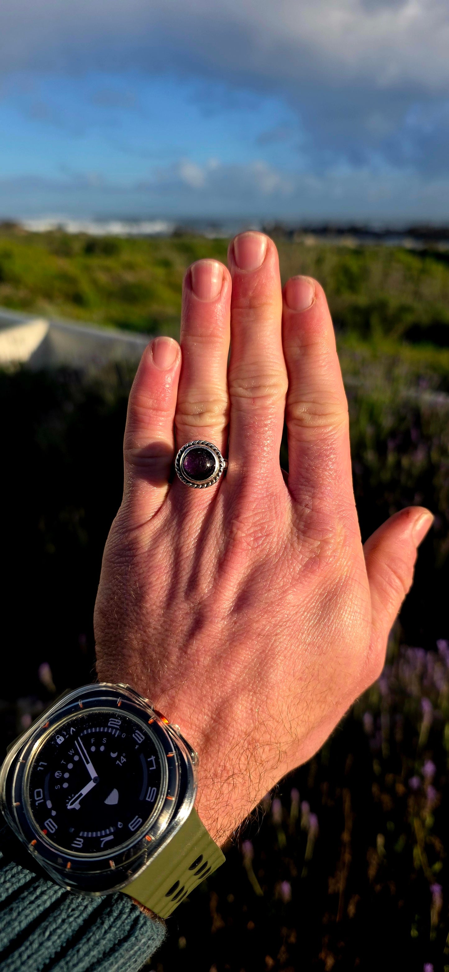 This striking handcrafted Kabwe sterling silver ring features a glowing rounded amethyst cabochon, elegantly tube-set within a beautifully raised and richly textured domed setting.