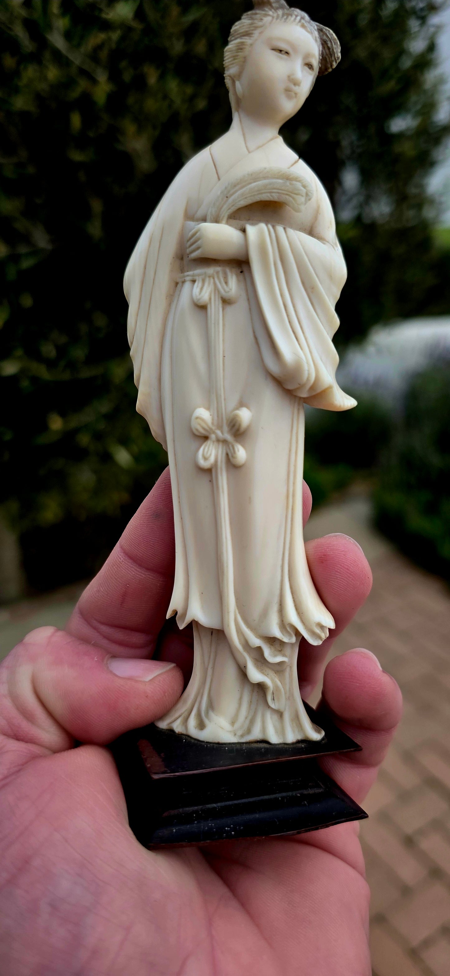 A wonderfully refined 19th-century hand-carved Japanese ivory sculpture, depicting a graceful Bijin (meaning "beautiful woman") elegantly dressed in flowing traditional robes and delicately holding an uchiwa (rigid ceremonial fan).