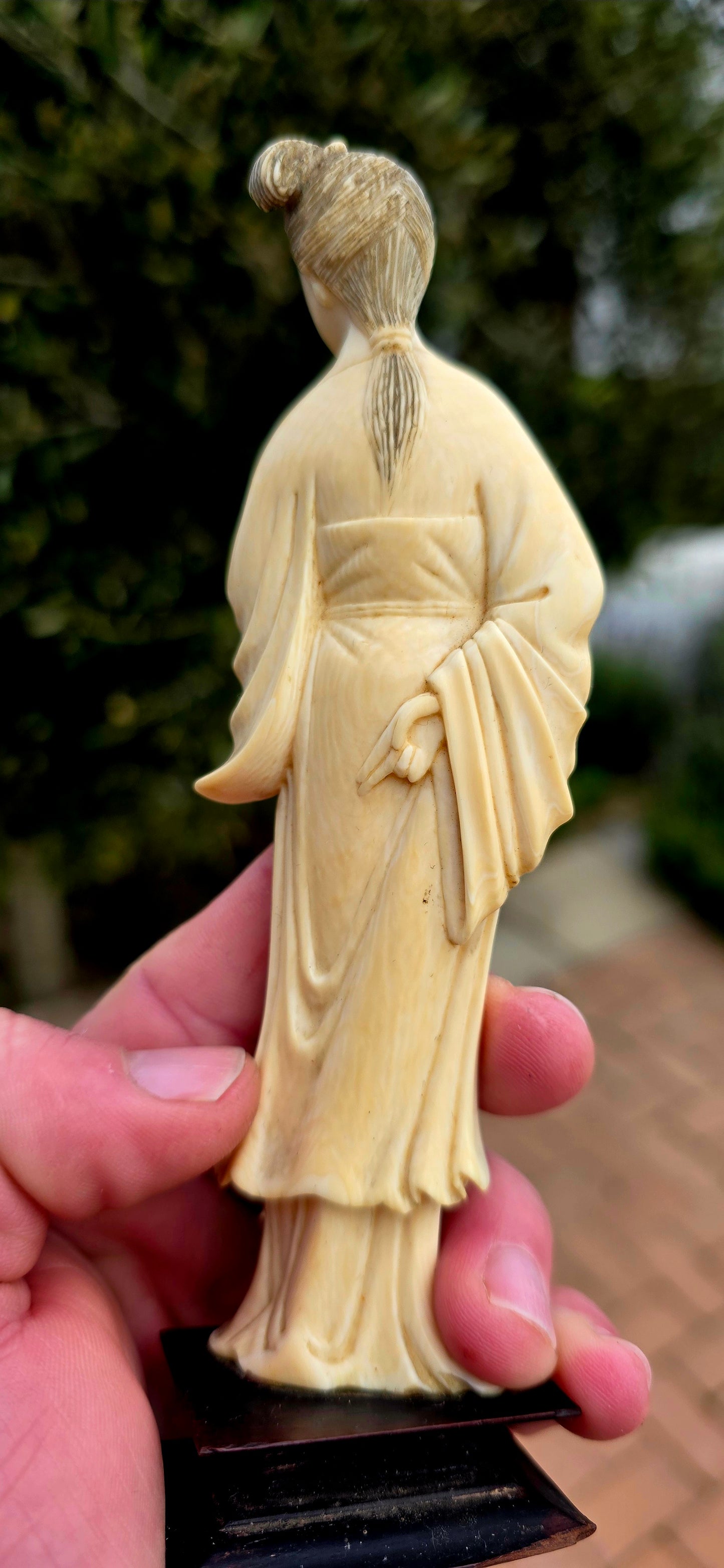 A wonderfully refined 19th-century hand-carved Japanese ivory sculpture, depicting a graceful Bijin (meaning "beautiful woman") elegantly dressed in flowing traditional robes and delicately holding an uchiwa (rigid ceremonial fan).