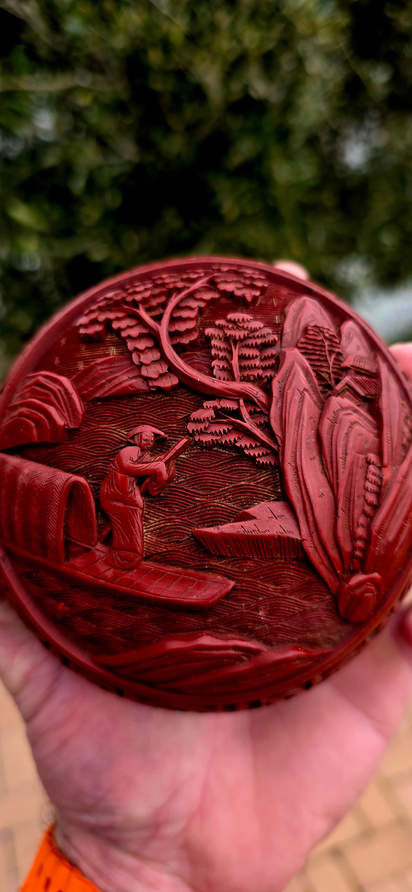 A magnificent Chinese cloisonné enamel and carved cinnabar circular box and lid, beautifully decorated with a tranquil riverside landscape depicting a lone scholar crossing the water toward towering mountains and a secluded pavilion.