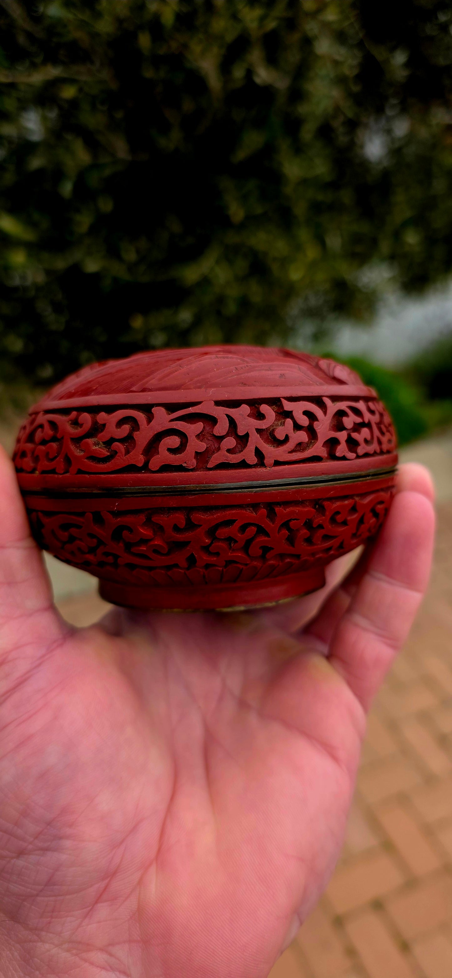 A magnificent Chinese cloisonné enamel and carved cinnabar circular box and lid, beautifully decorated with a tranquil riverside landscape depicting a lone scholar crossing the water toward towering mountains and a secluded pavilion.