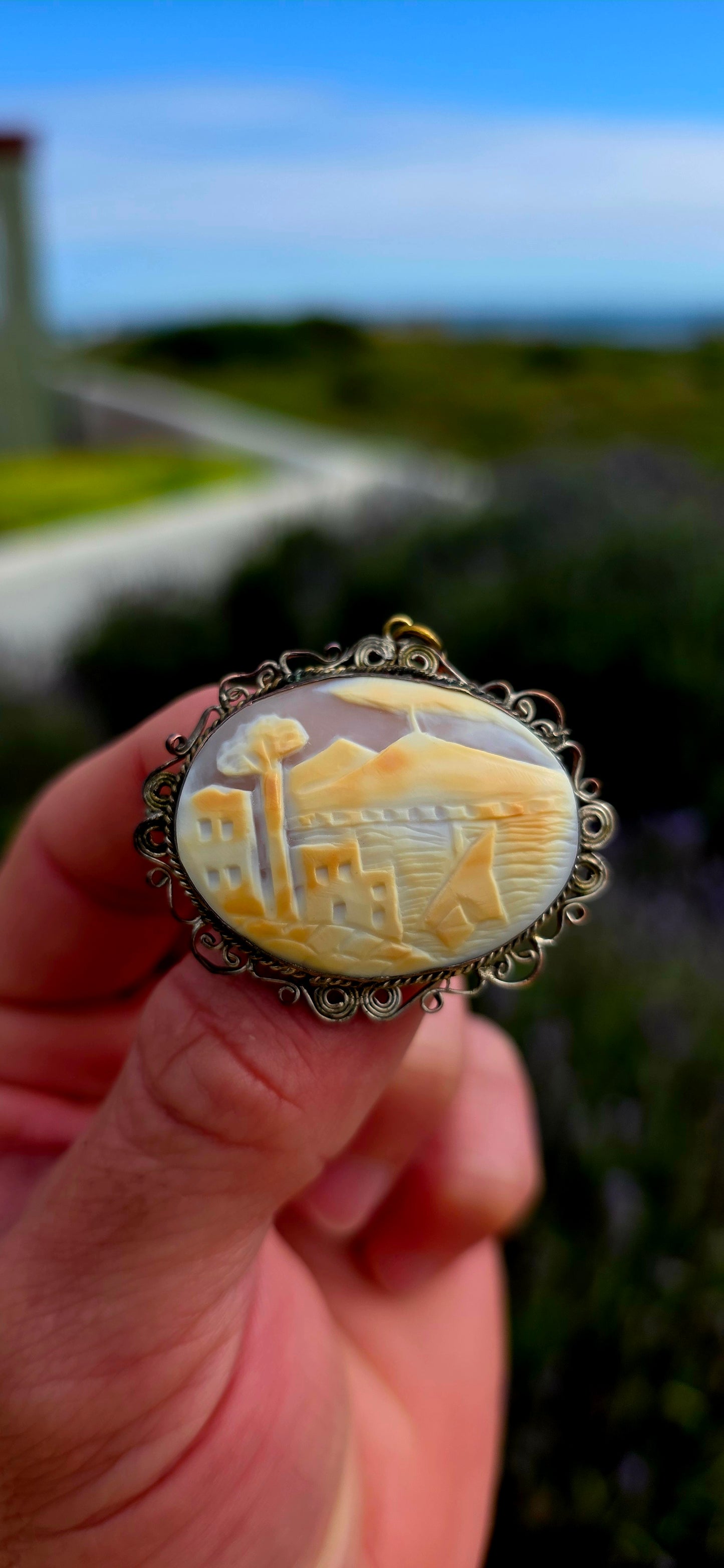 Beautifully handcrafted, this vintage silver-plated filigree cameo features a finely hand-carved conch shell depicting a tranquil coastal village scene.