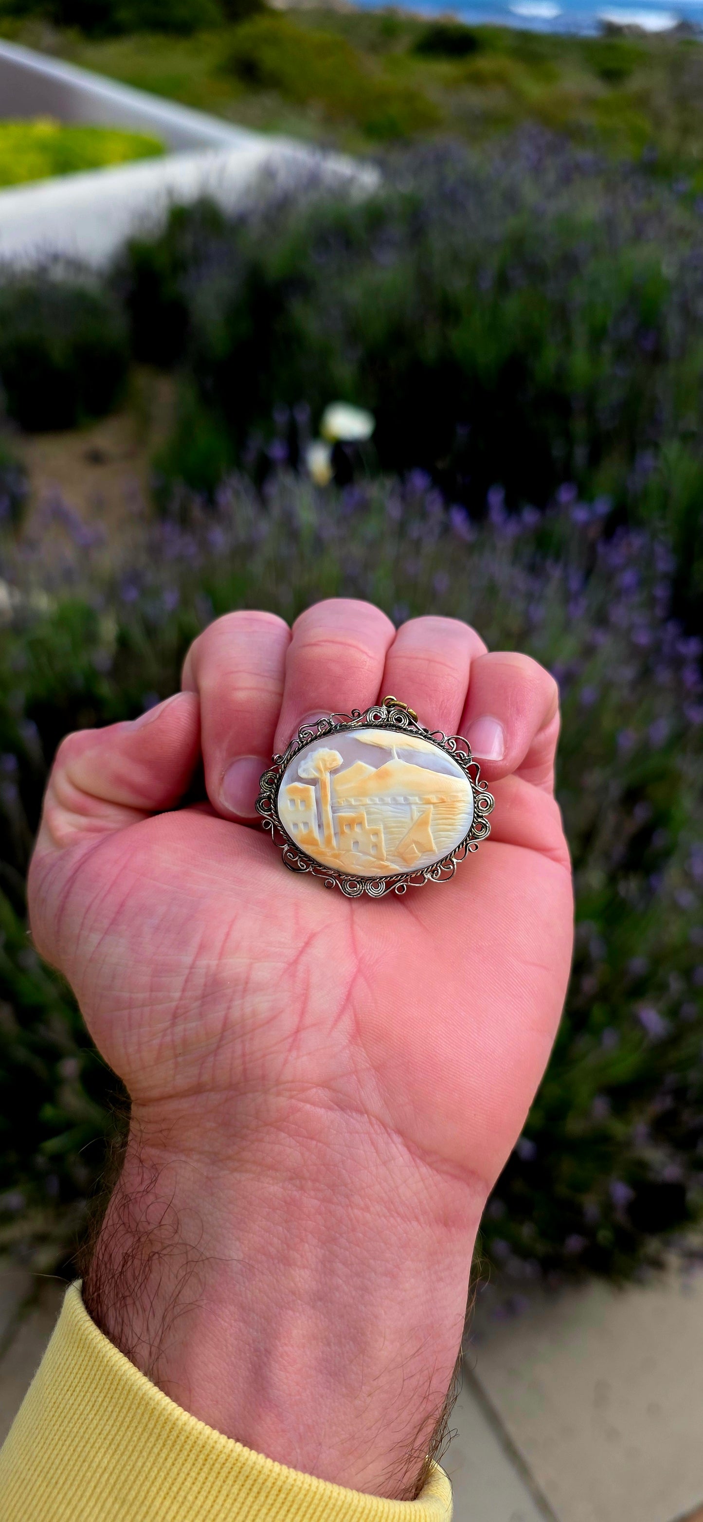 Beautifully handcrafted, this vintage silver-plated filigree cameo features a finely hand-carved conch shell depicting a tranquil coastal village scene.
