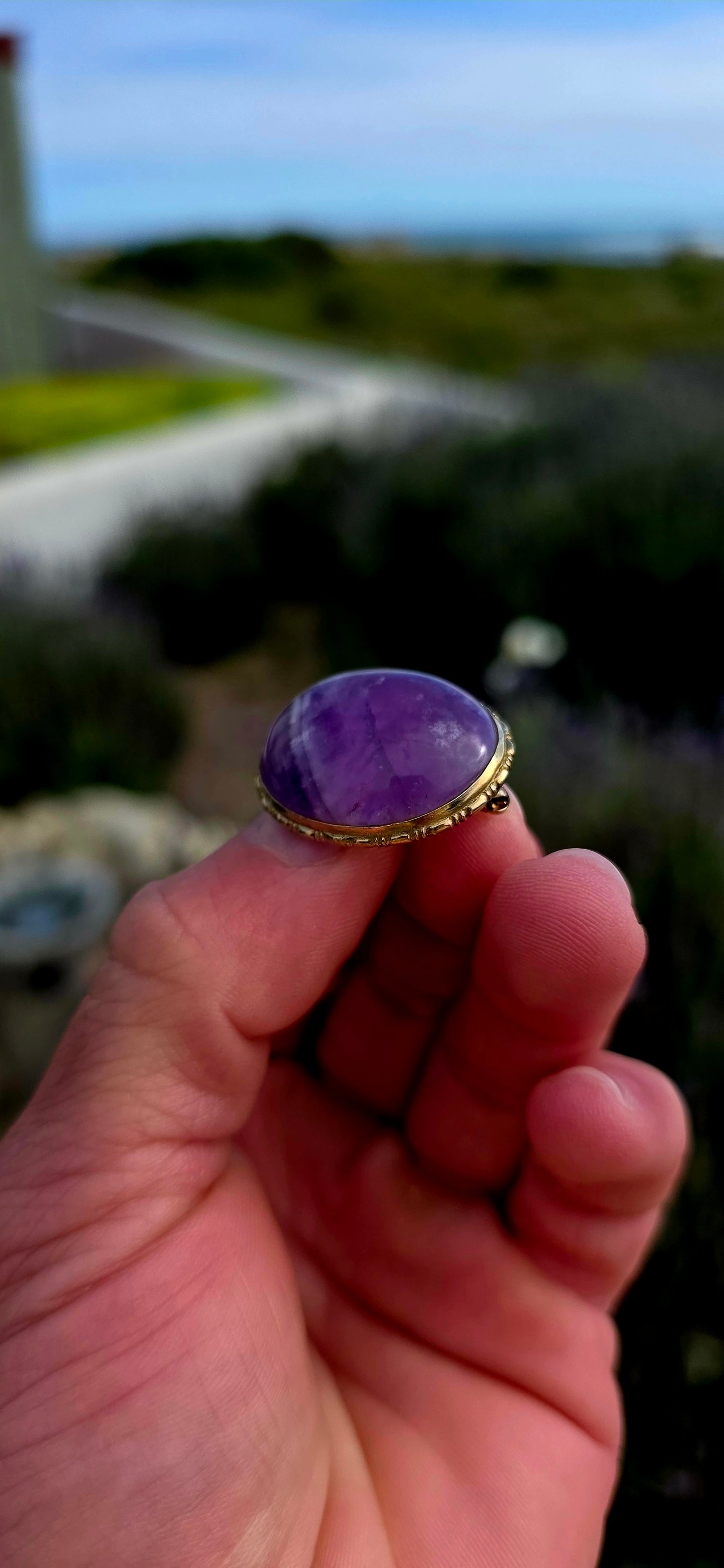 A truly beautiful antique treasure, this 10ct yellow gold brooch showcases a generously sized natural oval amethyst cabochon, celebrated for its rich royal-purple hues and soft, glowing lustre.