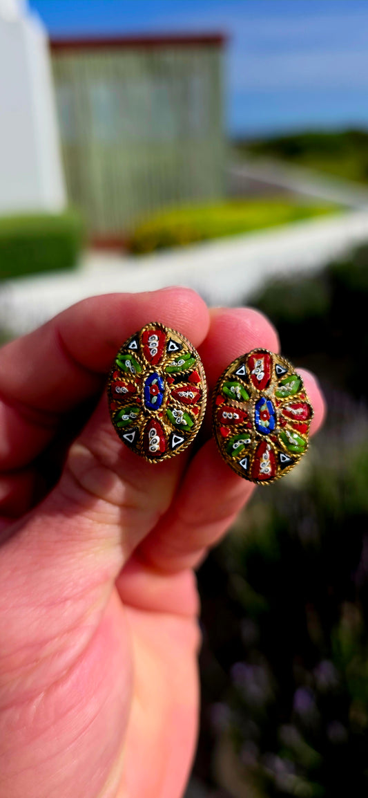 A charming pair of antique oval micro mosaic clip-on earrings, beautifully handcrafted using hundreds of individually placed glass tesserae to create intricate floral and geometric patterns in vibrant shades of red, blue, green, white and black.