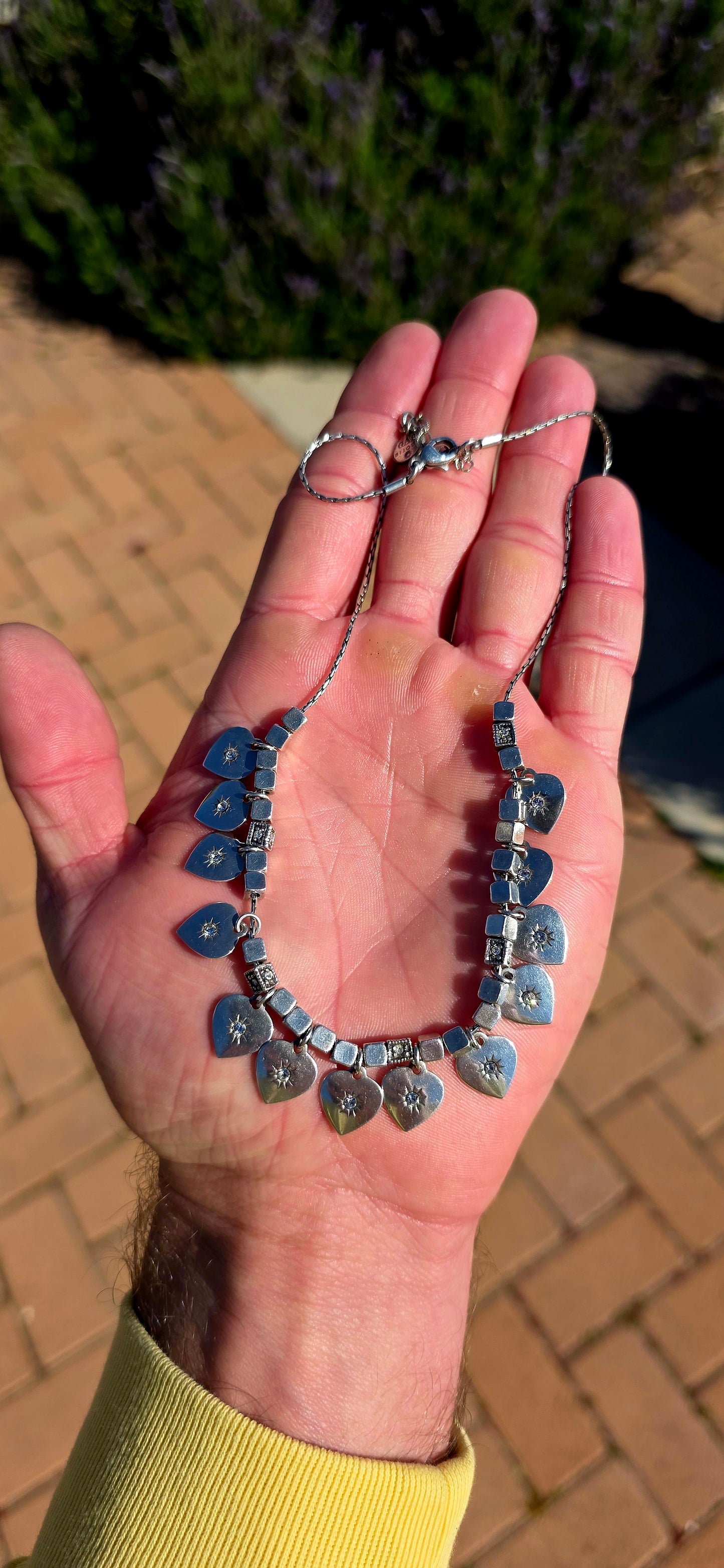 A beautifully feminine statement piece by renowned French jewellery house Gas Bijoux. This designer silver-plated necklace features a graceful row of heart dangles, each adorned with sparkling Swarovski crystal rhinestones in delicate starburst settings.