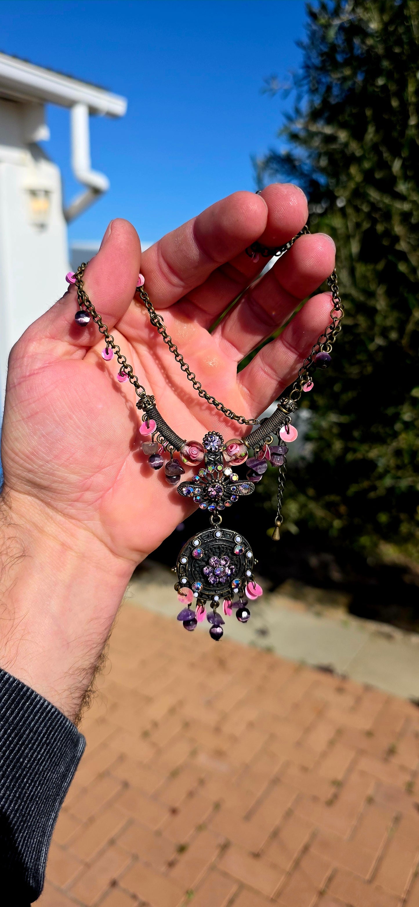 A beautifully handmade statement costume necklace, crafted in antique-bronze-tone metal and dripping with gorgeous shades of amethyst, violet, lavender and pink.