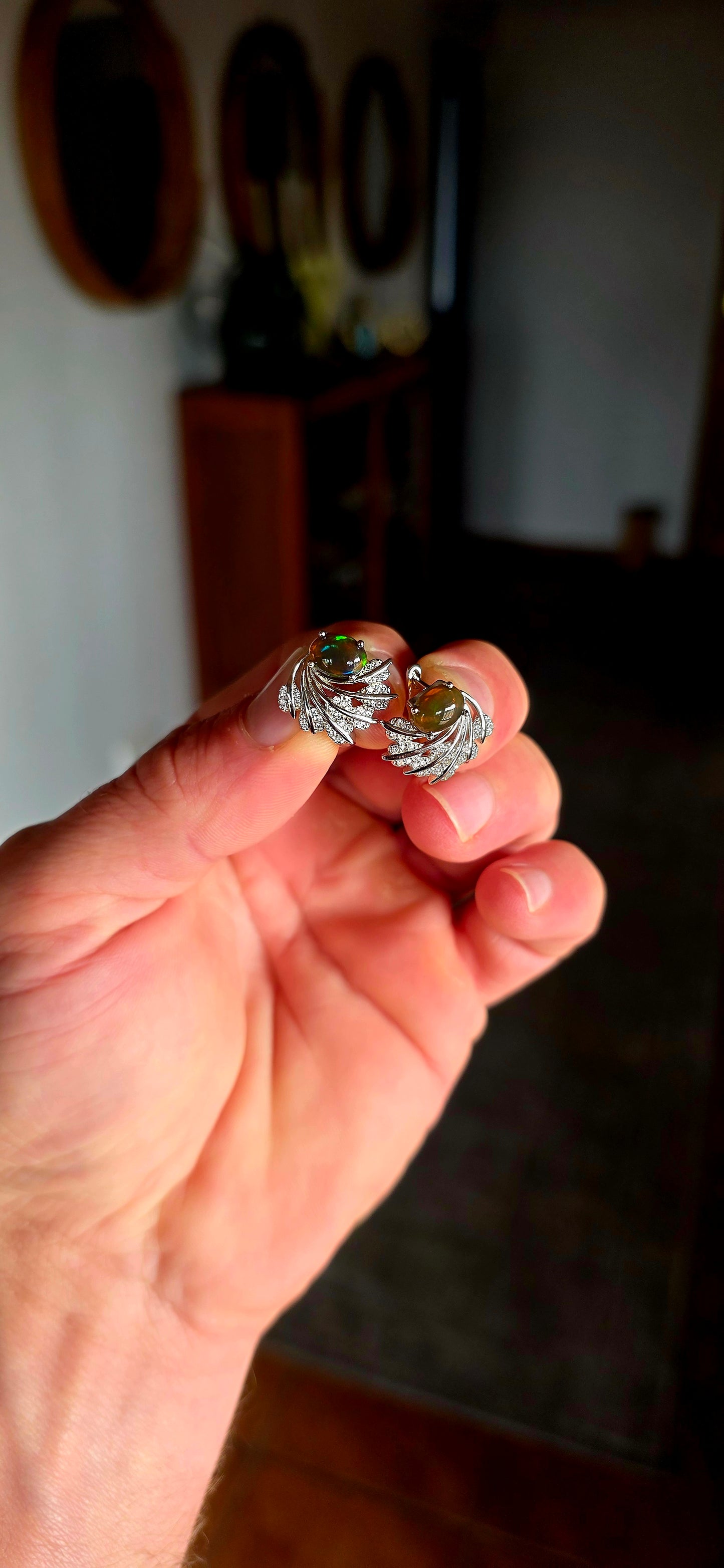 These enchanting sterling silver earrings each feature an oval dark-bodied Ethiopian opal cabochon, displaying those magical flashes of green, orange, gold and blue as they move through the light.