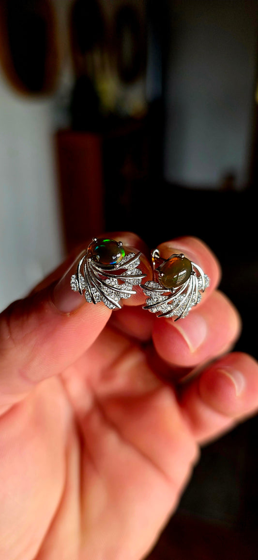 These enchanting sterling silver earrings each feature an oval dark-bodied Ethiopian opal cabochon, displaying those magical flashes of green, orange, gold and blue as they move through the light.