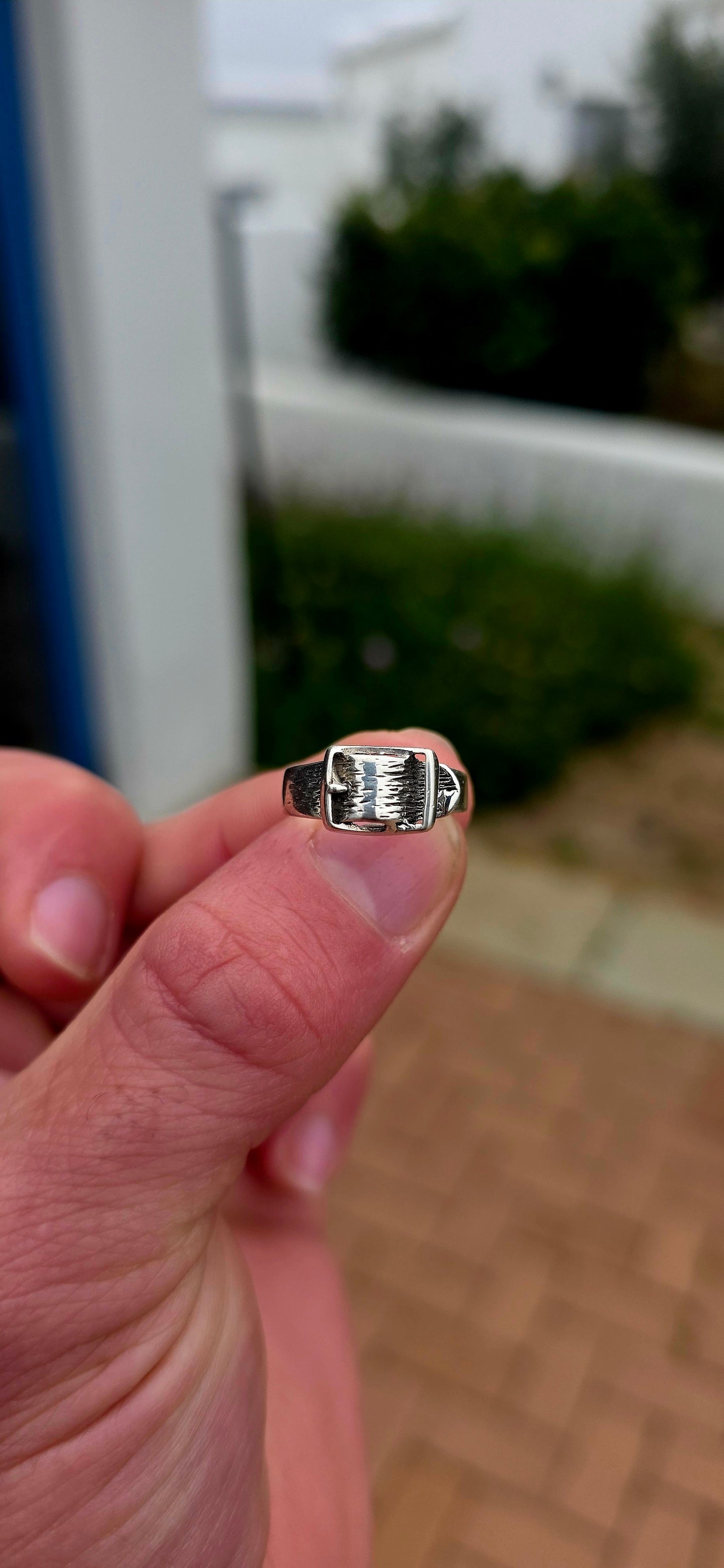 A vintage sterling silver Victorian Revival pinky ring, fashioned in the form of a miniature belt and buckle, complete with wonderful textured detailing and a raised buckle across the front.