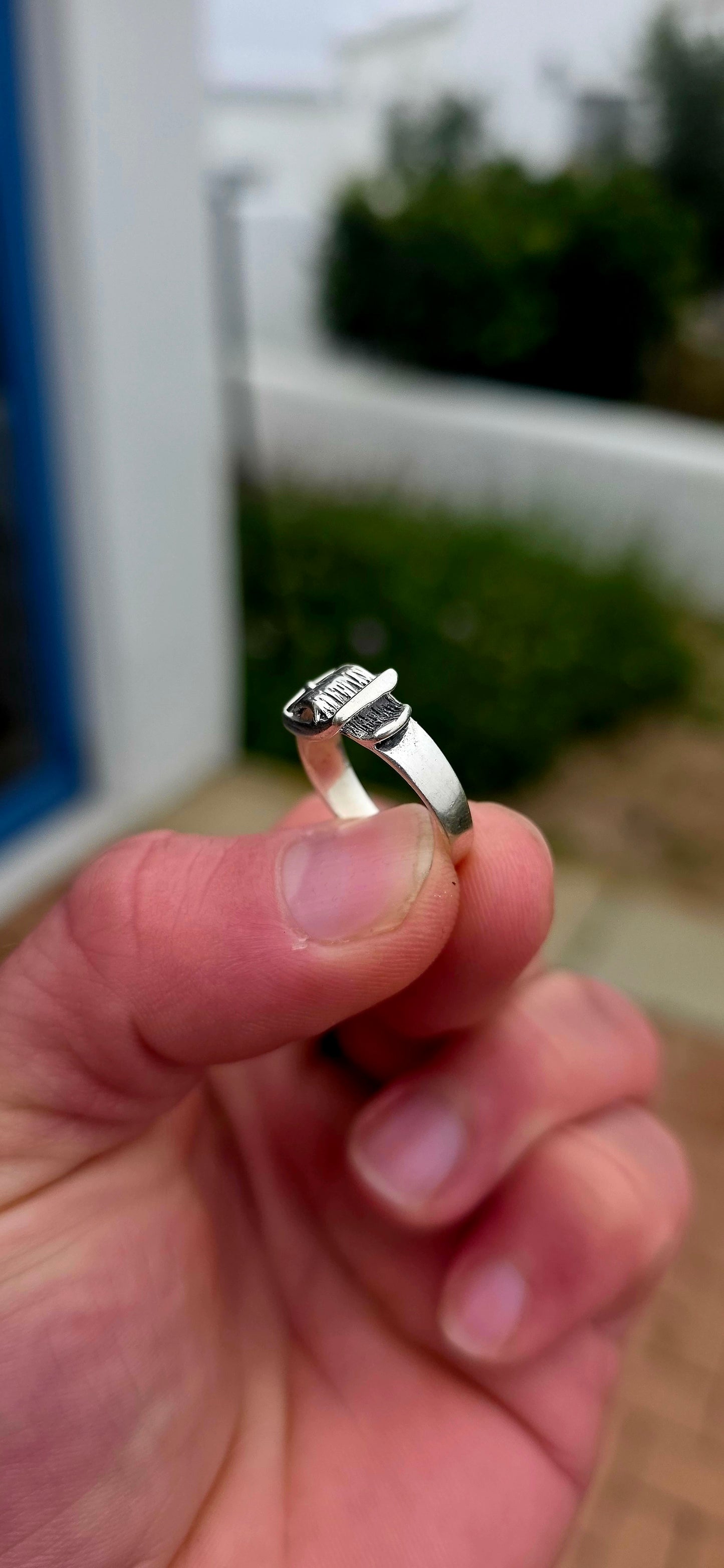 A vintage sterling silver Victorian Revival pinky ring, fashioned in the form of a miniature belt and buckle, complete with wonderful textured detailing and a raised buckle across the front.