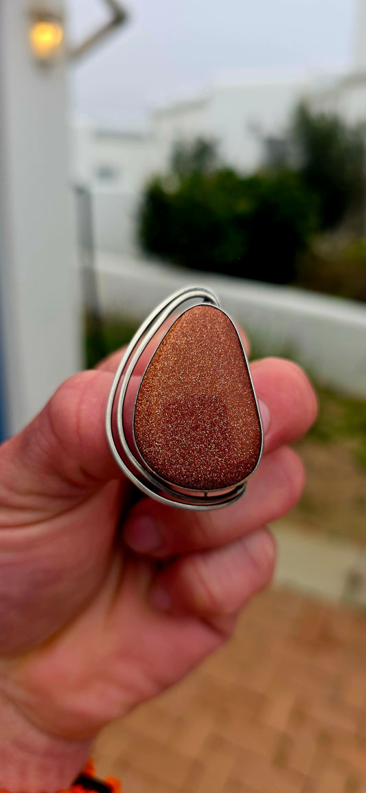 A striking vintage Israeli Modernist sterling silver brooch and pendant, centred around an impressively sized freeform goldstone cabochon that absolutely glitters with thousands of tiny coppery-gold flashes.