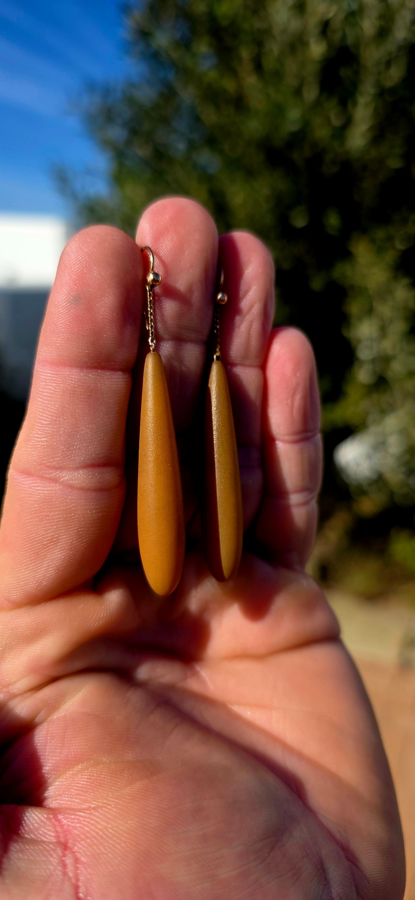 An absolutely fabulous and wonderfully unusual pair of antique Edwardian-era drop earrings, combining warm 9ct rose gold with beautifully elongated caramel-brown Bakelite torpedo drops.