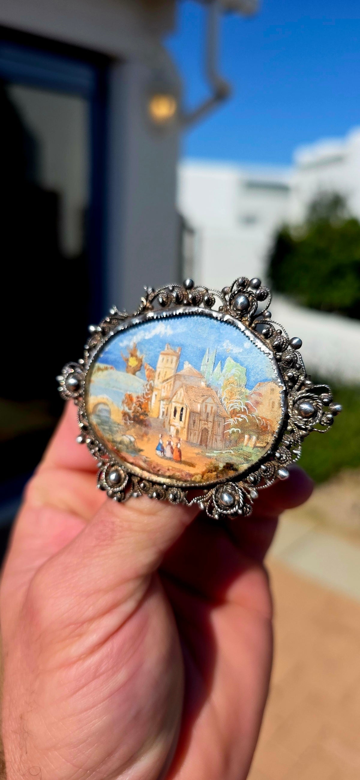 A truly beautiful and oversized antique Victorian-era sterling silver brooch, centred with a wonderfully detailed hand-painted miniature landscape scene, preserved beneath its original domed glass.