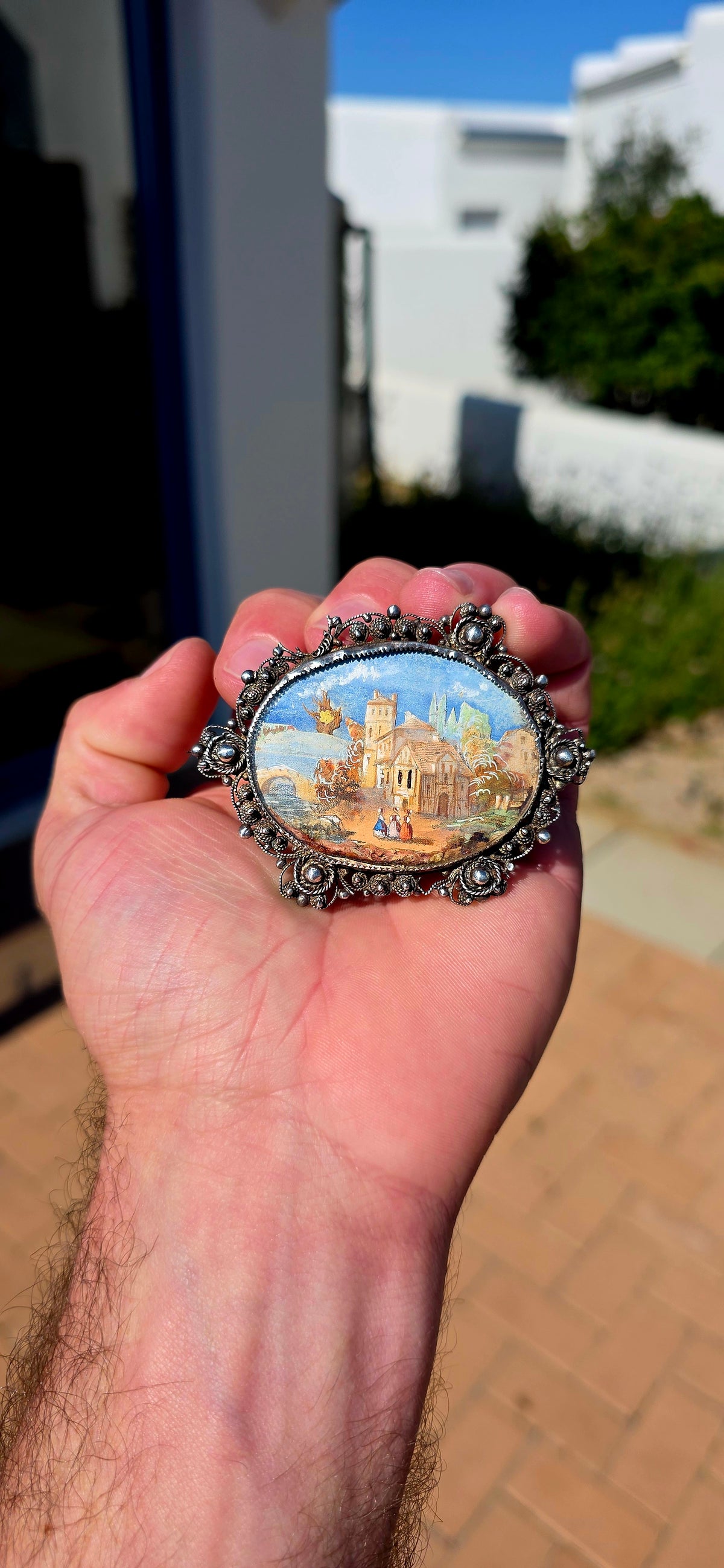 A truly beautiful and oversized antique Victorian-era sterling silver brooch, centred with a wonderfully detailed hand-painted miniature landscape scene, preserved beneath its original domed glass.