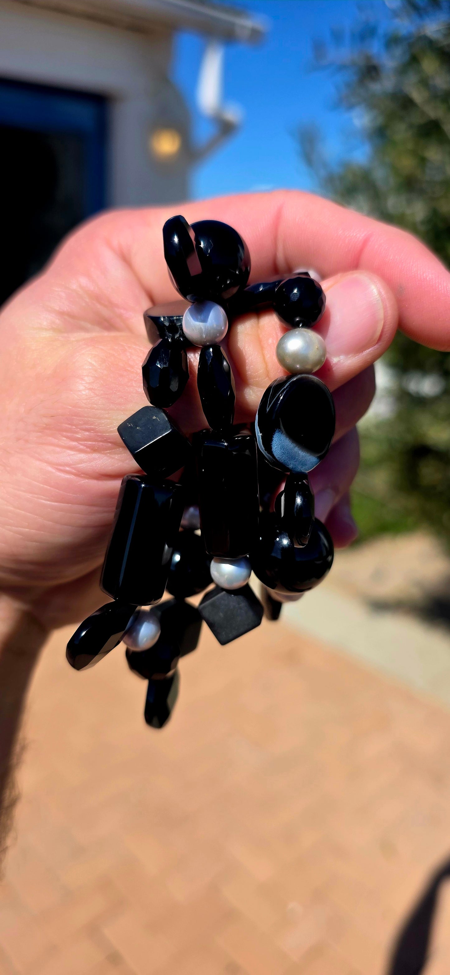 A fabulous collection of chunky gemstone stretch bracelets in dramatic shades of glossy black, beautifully contrasted with luminous freshwater pearls.