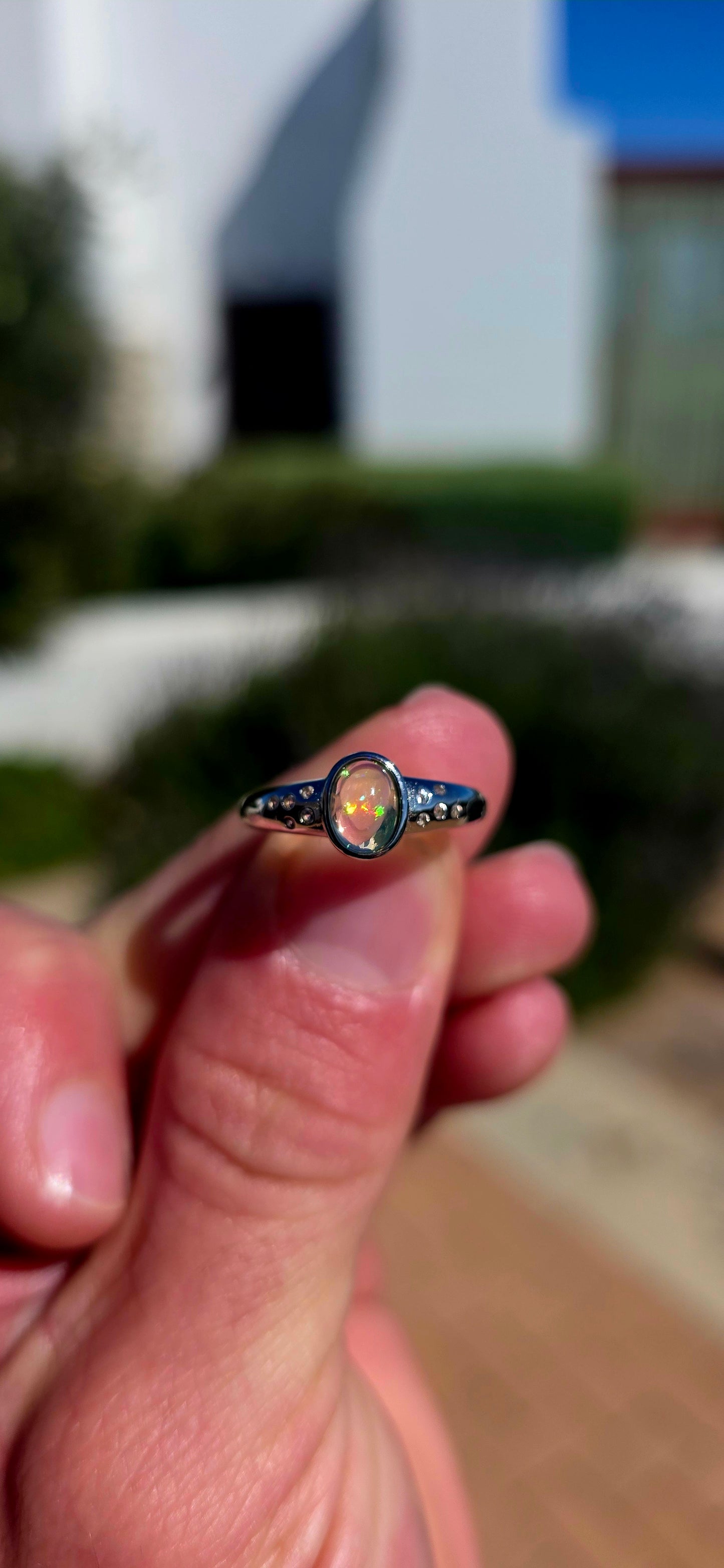 Pure little flashes of magic! This beautiful sterling silver solitaire-style ring centres around an oval Ethiopian Welo water opal cabochon, smoothly tube-set to really let that incredible natural play-of-colour take centre stage.