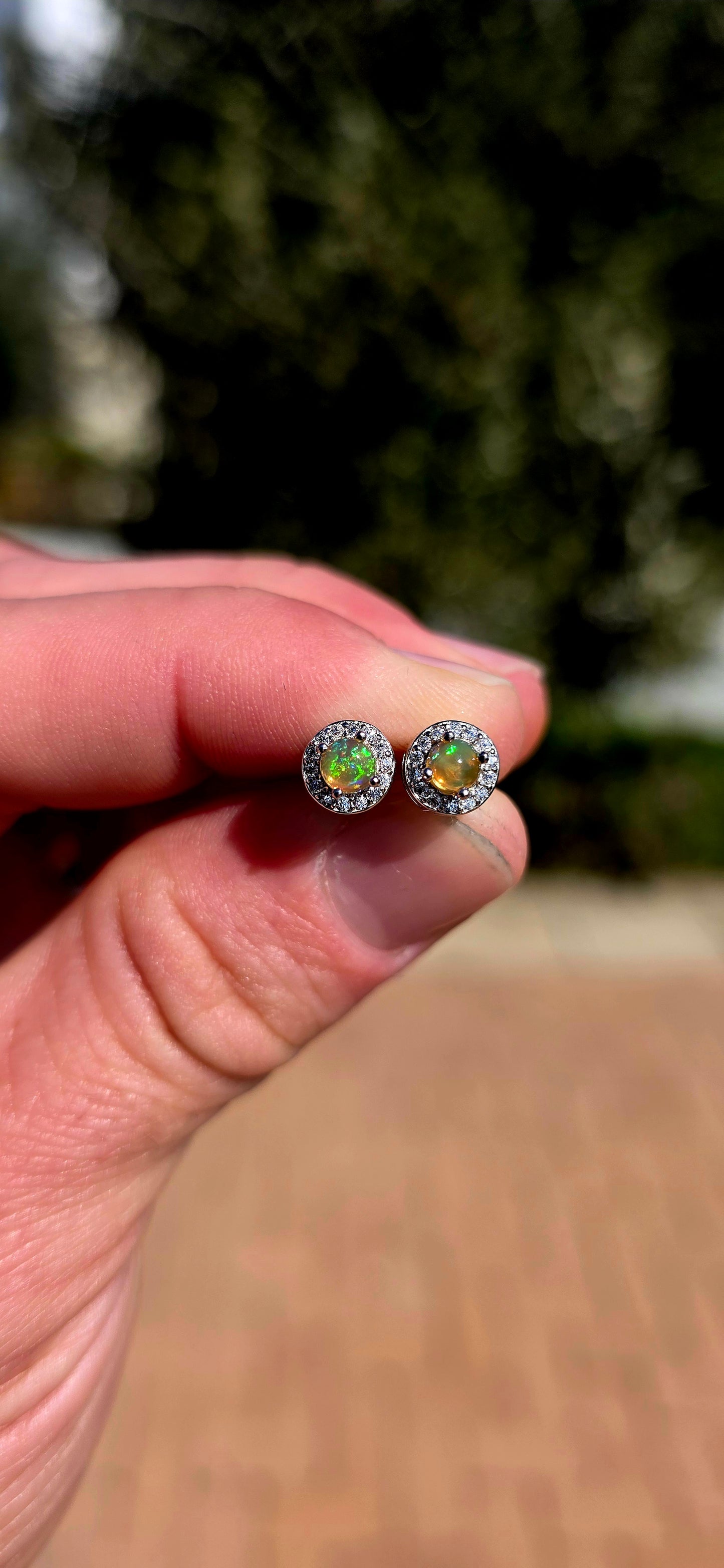 Small but absolutely magical! These beautiful stud earrings are crafted in solid sterling silver, each centred with a round natural Ethiopian opal cabochon, securely prong-set and surrounded by a delicate halo of sparkling CZ gemstones.
