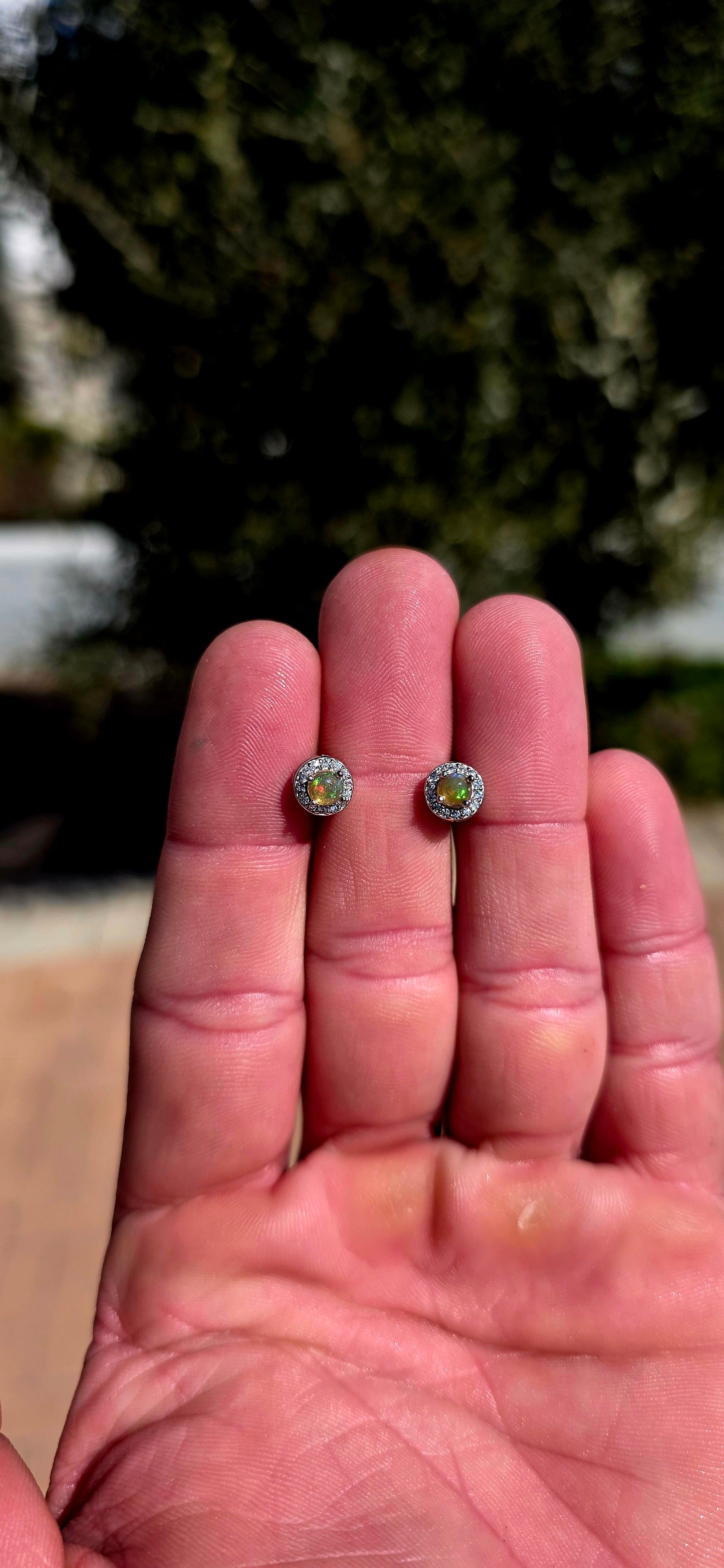 Small but absolutely magical! These beautiful stud earrings are crafted in solid sterling silver, each centred with a round natural Ethiopian opal cabochon, securely prong-set and surrounded by a delicate halo of sparkling CZ gemstones.
