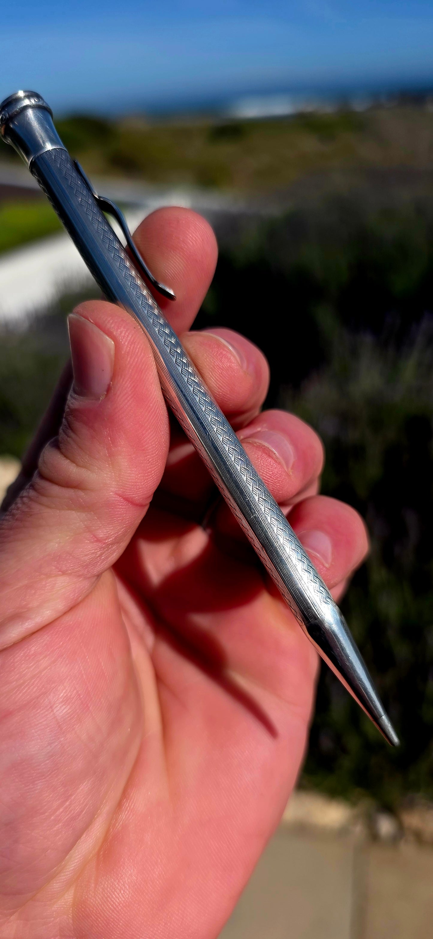 Dating to circa 1920s, this antique mechanical propelling pencil is crafted in solid sterling silver, with the slender body beautifully decorated in a fine engine-turned geometric pattern.