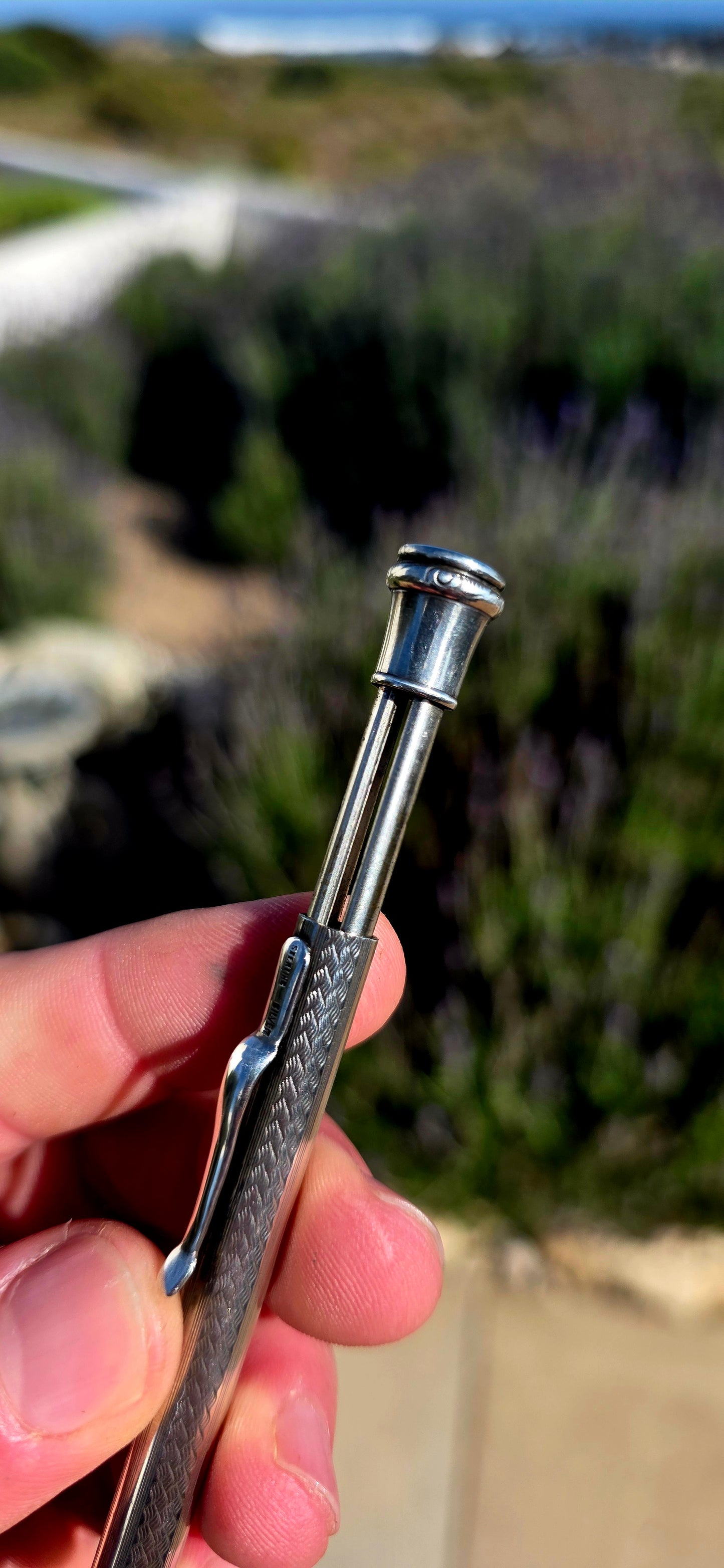 Dating to circa 1920s, this antique mechanical propelling pencil is crafted in solid sterling silver, with the slender body beautifully decorated in a fine engine-turned geometric pattern.