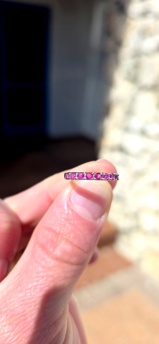 Delicate, feminine and made for stacking! This petite sterling silver half-eternity ring features a neat row of nine round-cut natural rubies, individually set across the front of the slender band.
