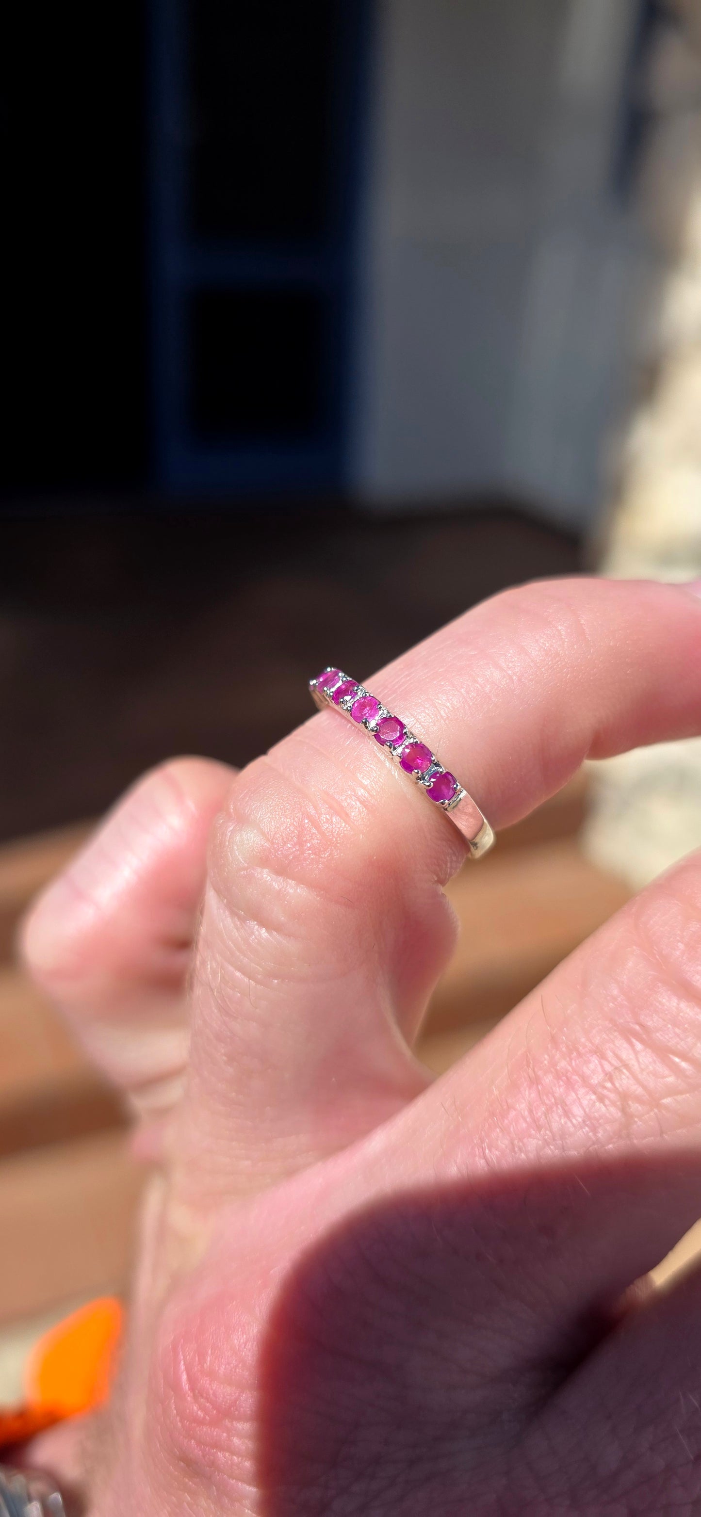 Delicate, feminine and made for stacking! This petite sterling silver half-eternity ring features a neat row of nine round-cut natural rubies, individually set across the front of the slender band.