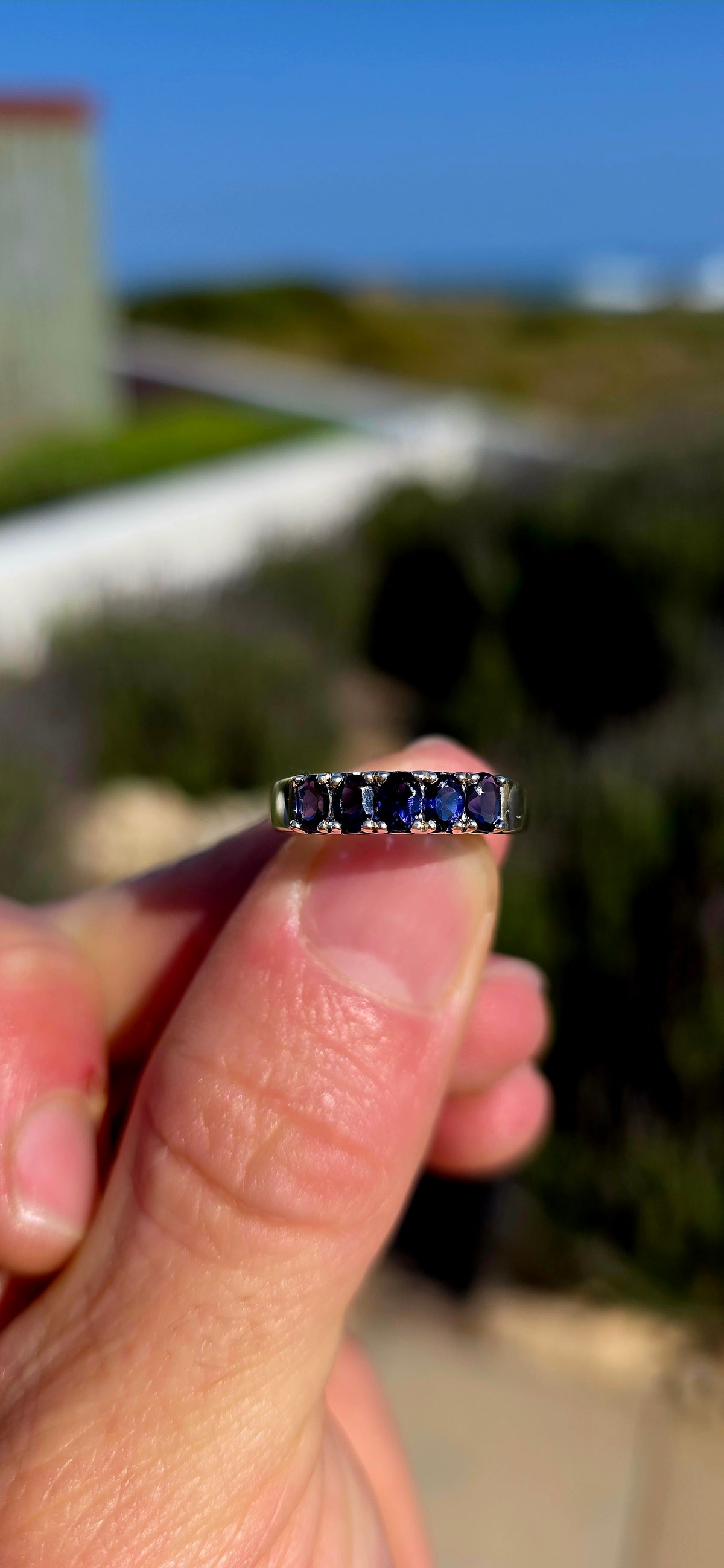 Understated, elegant and wonderfully easy to wear! This sterling silver half-eternity stacking ring is beautifully prong-set across the front with five oval-cut natural iolite gemstones.