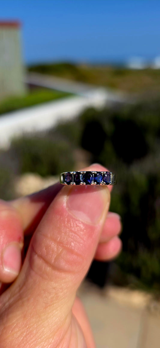 Understated, elegant and wonderfully easy to wear! This sterling silver half-eternity stacking ring is beautifully prong-set across the front with five oval-cut natural iolite gemstones.
