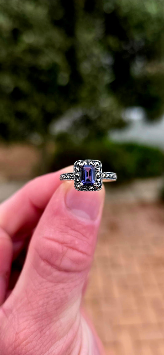Crafted in solid sterling silver, this elegant solitaire ring centres around a beautifully emerald-cut iolite, raised within a classic four-prong setting