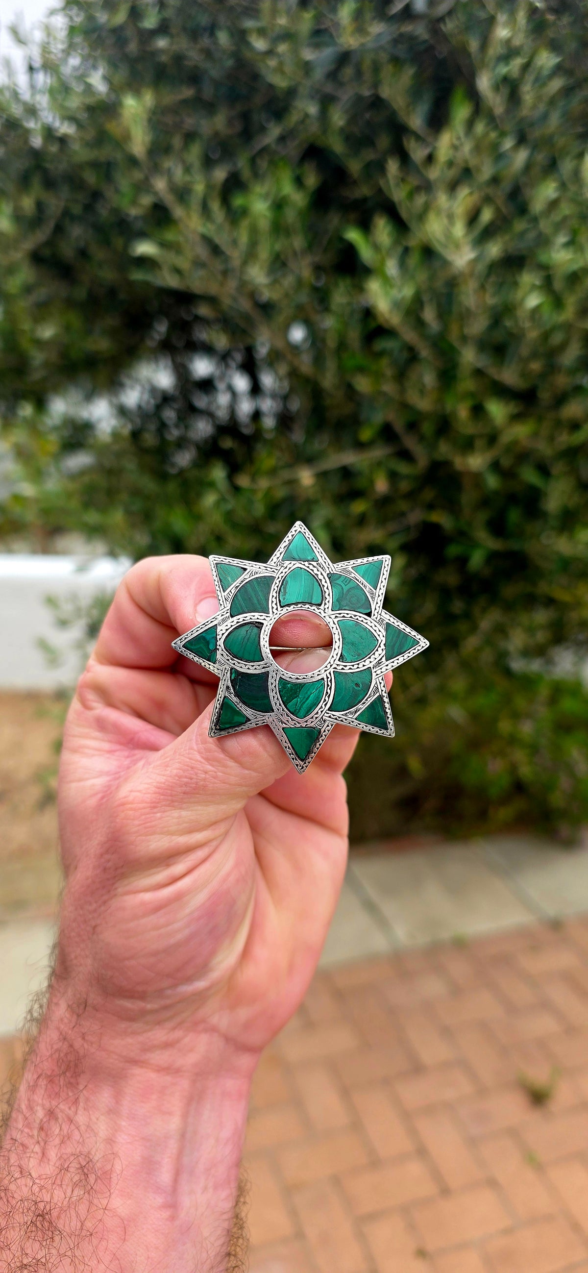 Dating to approximately the 1870s, this generously sized antique brooch is crafted in sterling silver and beautifully inlaid with individual sections of richly patterned natural malachite.