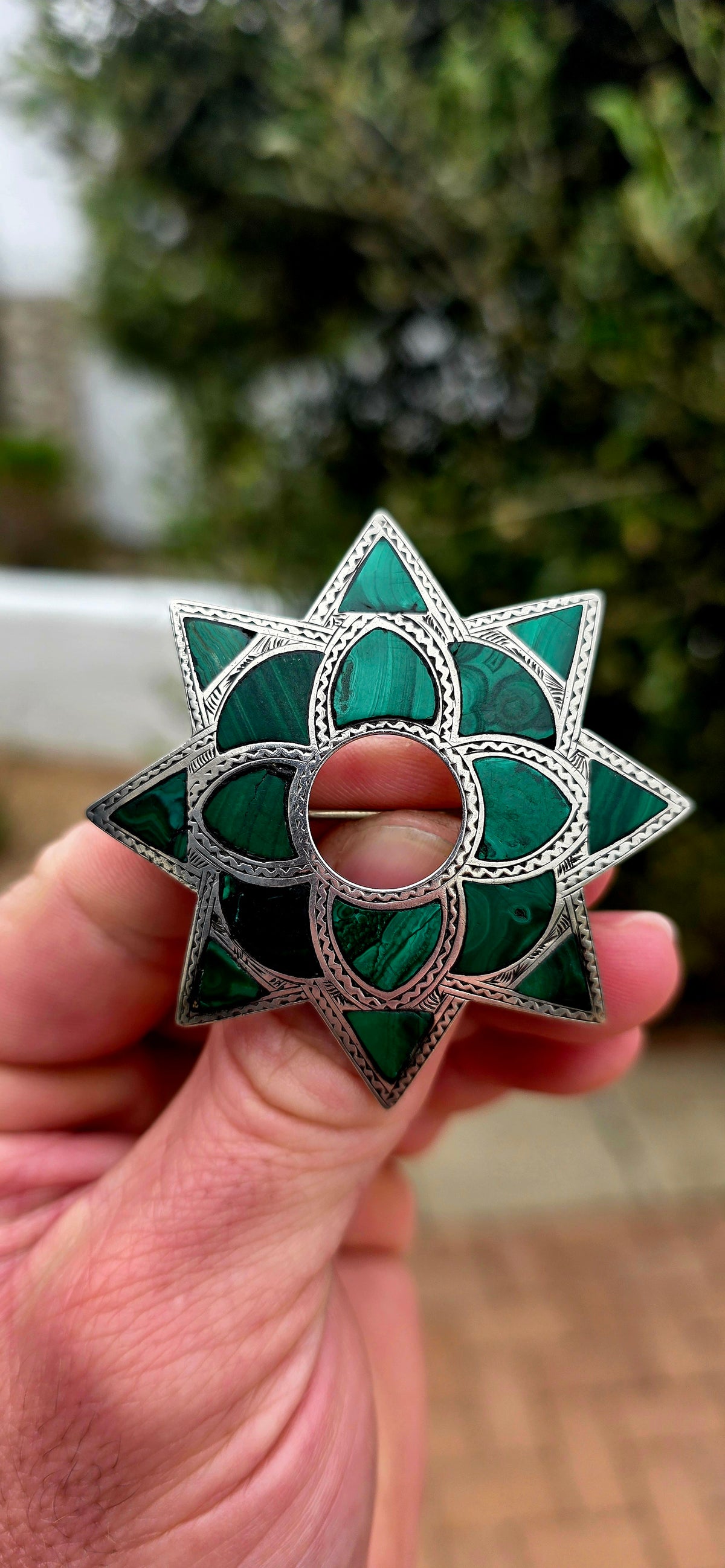 Dating to approximately the 1870s, this generously sized antique brooch is crafted in sterling silver and beautifully inlaid with individual sections of richly patterned natural malachite.