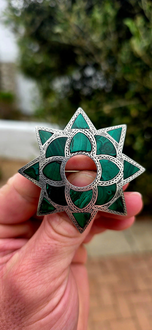 Dating to approximately the 1870s, this generously sized antique brooch is crafted in sterling silver and beautifully inlaid with individual sections of richly patterned natural malachite.