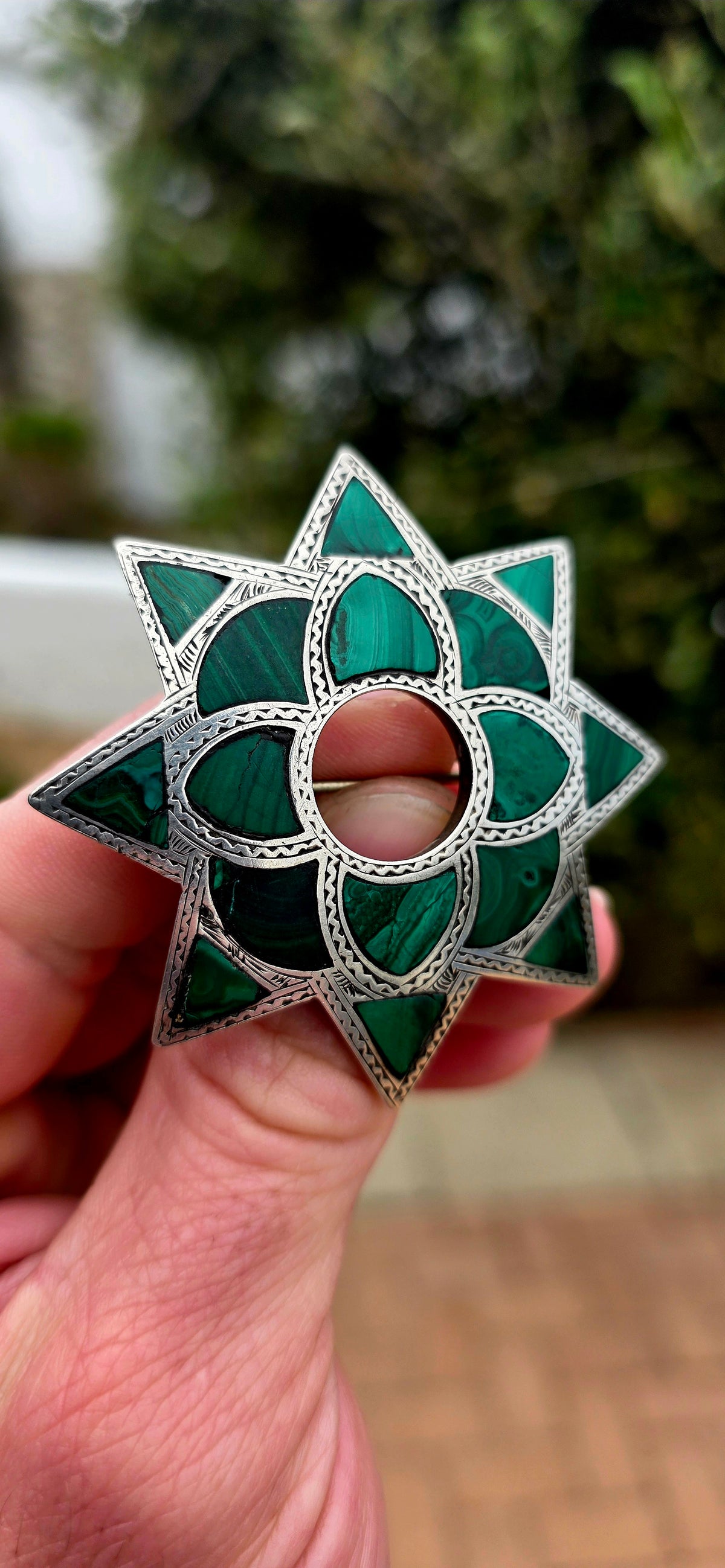 Dating to approximately the 1870s, this generously sized antique brooch is crafted in sterling silver and beautifully inlaid with individual sections of richly patterned natural malachite.