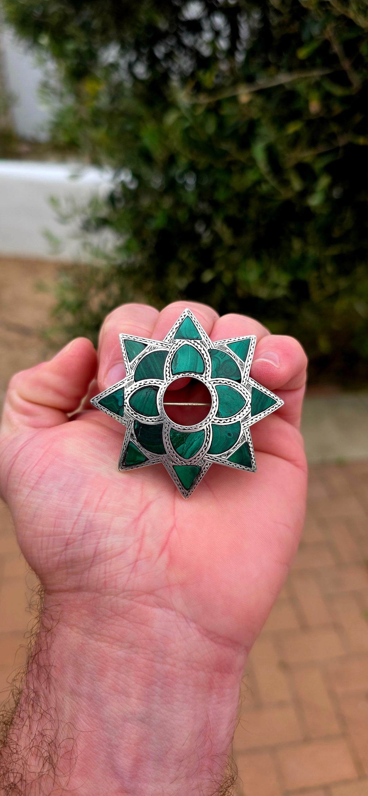Dating to approximately the 1870s, this generously sized antique brooch is crafted in sterling silver and beautifully inlaid with individual sections of richly patterned natural malachite.